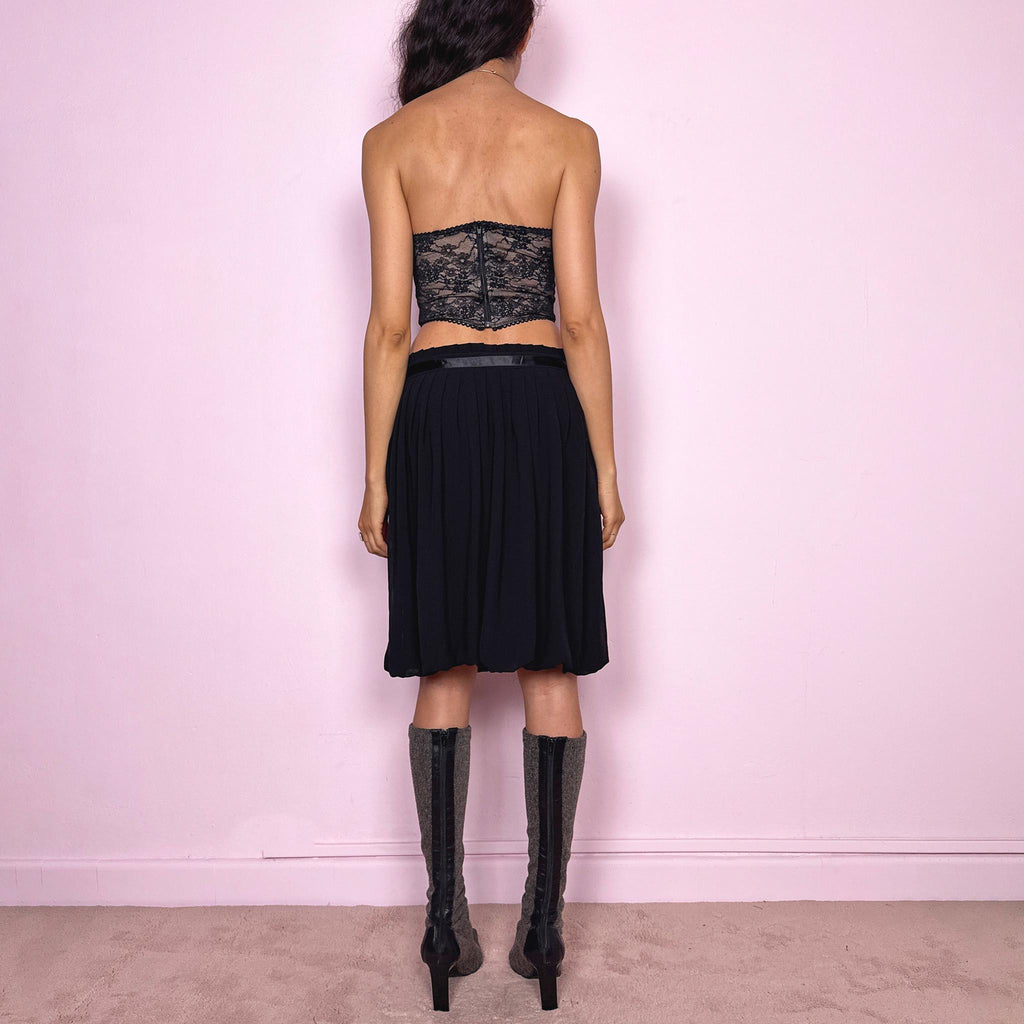 Vintage 2000s black bubble hem midi skirt featuring a pleated silhouette with side zip closure, front tie detail, and voluminous bubble hem. Romantic yet minimal with a subtle coquette party mood, ideal for formal occasions, evening looks, or darker feminine everyday styling. Can be worn high waisted for M or lower rise for S. From a French brand. Excellent vintage condition.