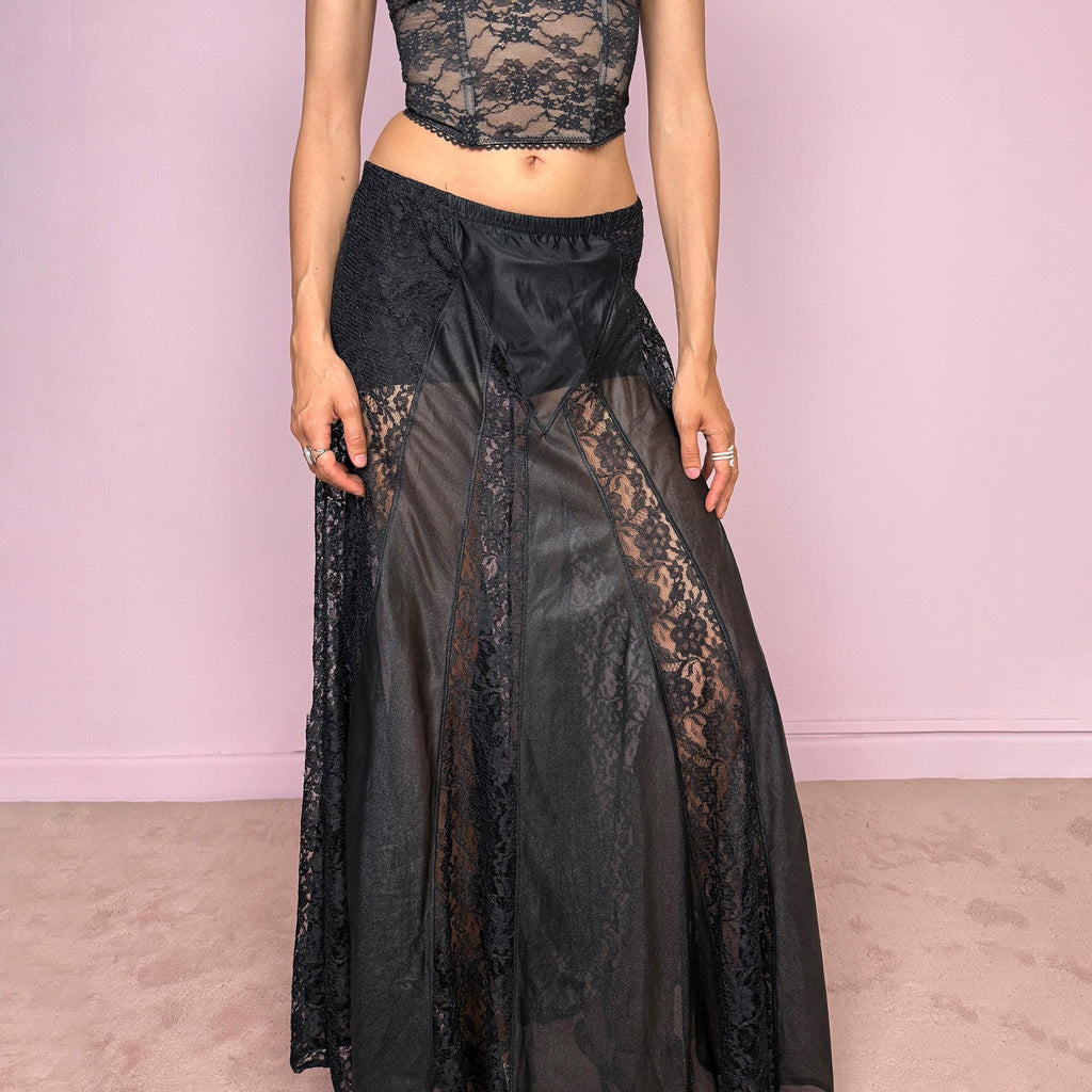 Vintage 90s black gothic maxi skirt with an elasticated waist and dramatic floor-length silhouette. Features sheer lace panels, semi-transparent mesh sections, and layered fabric construction for a dark romantic lingerie-inspired finish. Can be worn high waisted for M or lower rise for S. Made from 100% polyester. Great vintage condition.