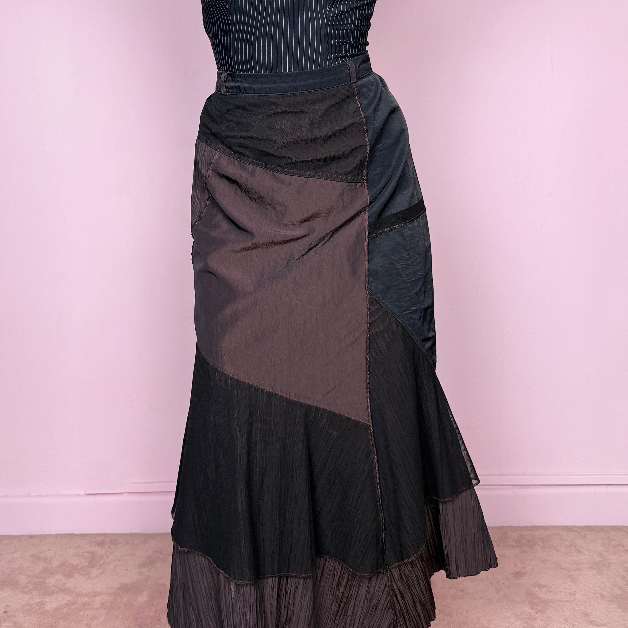 Vintage 2000s asymmetric layered midi skirt with a fitted waist, back zip closure, and structured non-stretch fit. Features black and brown asymmetric panels, crinkled texture, pleated hem detail, and mesh tulle overlays. Artistic Y2K piece with an understated dark avant-garde feel. Can be worn high waisted for S or lower rise for XS and XXS. From a French brand. Excellent vintage condition.