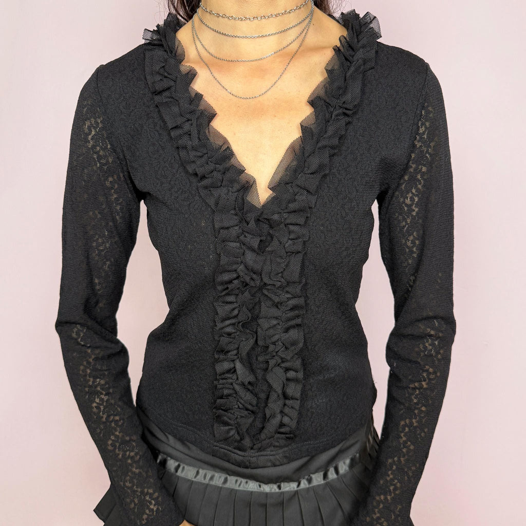 Vintage 2000s black stretch lace mesh top, designed with a fitted silhouette, sheer floral lace texture, long sleeves, and dramatic ruffle detailing through the deep V neckline. The layered mesh ruffles add a dark romantic, gothic, and feminine feel ideal for evening outfits. Made from 100% polyamide. Excellent vintage condition.