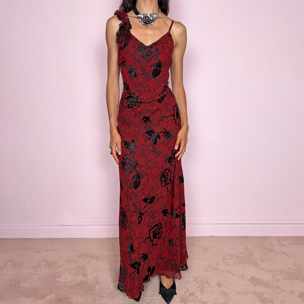 Vintage 2000s red and black floral maxi dress with a fitted silhouette, spaghetti straps, and a dramatic ruffle detail at one shoulder. Designed with a V neckline, long flowing skirt, and black floral motifs over a deep red base, creating a dark romantic evening look. Lightweight with no stretch, a softly semi-sheer outer layer, and black lining, perfect for formal occasions. Composition label is missing, so the exact fabric is unknown. Excellent vintage condition.