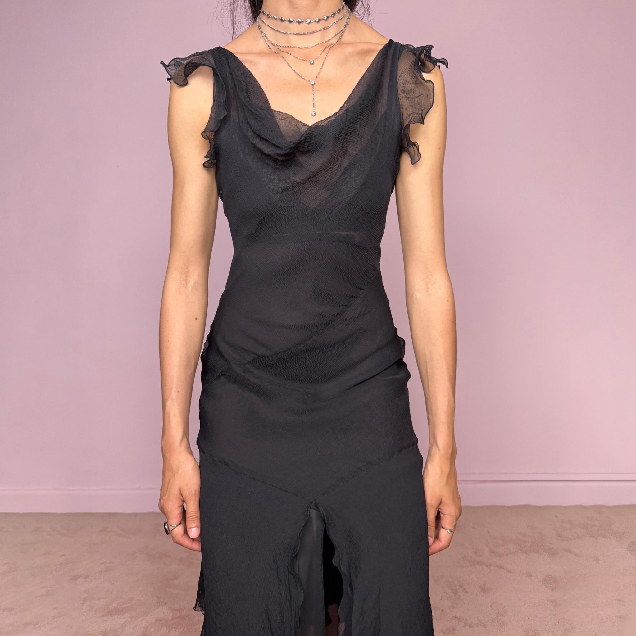 Vintage 2000s black midi dress with a romantic draped silhouette and semi-sheer layered construction. Designed with a cowl-style neckline, delicate ruffled cap sleeves, fitted waist, front slit detail, and fluid layered asymmetrical hem for an elegant dark evening look. The outer layer looks and feels like silk, but all labels are missing, so the exact fabric composition is unknown. Excellent vintage condition.