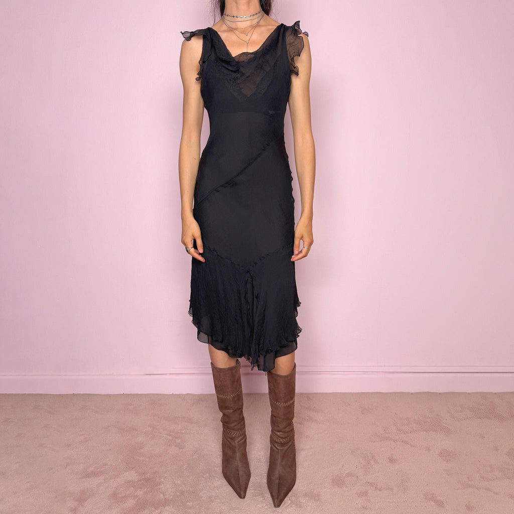 Vintage 2000s black midi dress with a romantic draped silhouette and semi-sheer layered construction. Designed with a cowl-style neckline, delicate ruffled cap sleeves, fitted waist, front slit detail, and fluid layered asymmetrical hem for an elegant dark evening look. The outer layer looks and feels like silk, but all labels are missing, so the exact fabric composition is unknown. Excellent vintage condition.