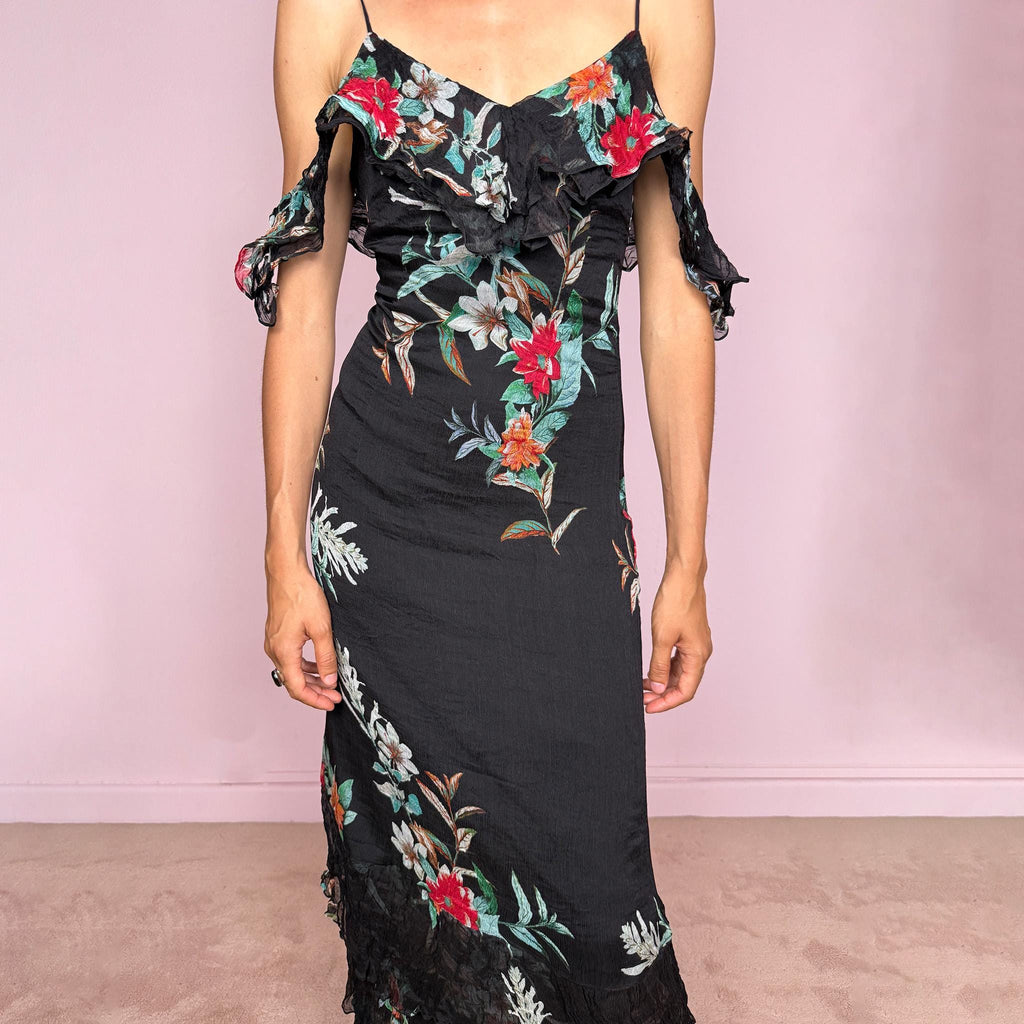 Vintage 2000s Guess Los Angeles black floral maxi dress with a romantic off-shoulder silhouette, delicate adjustable spaghetti straps, and dramatic ruffle detailing across the bust and sleeves. Designed with a fitted body, side zip closure, softly flared maxi skirt, and sheer textured floral panels through the hem. A dreamy statement evening dress, perfect for summer occasions.
