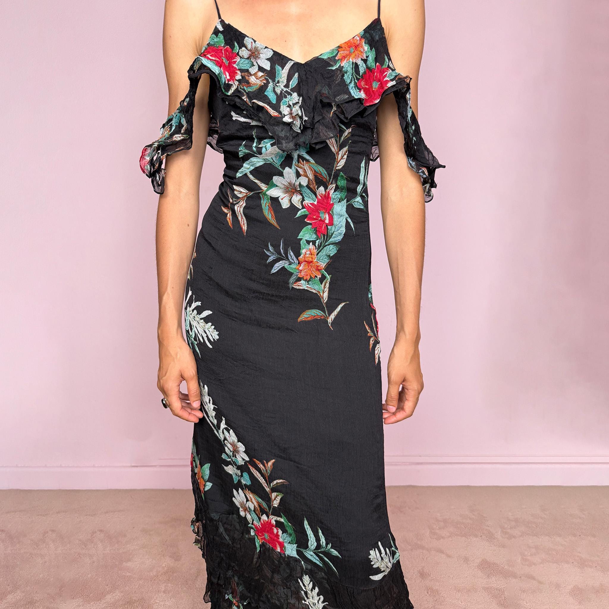 Vintage 2000s Guess Los Angeles black floral maxi dress with a romantic off-shoulder silhouette, delicate adjustable spaghetti straps, and dramatic ruffle detailing across the bust and sleeves. Designed with a fitted body, side zip closure, softly flared maxi skirt, and sheer textured floral panels through the hem. A dreamy statement evening dress, perfect for summer occasions.