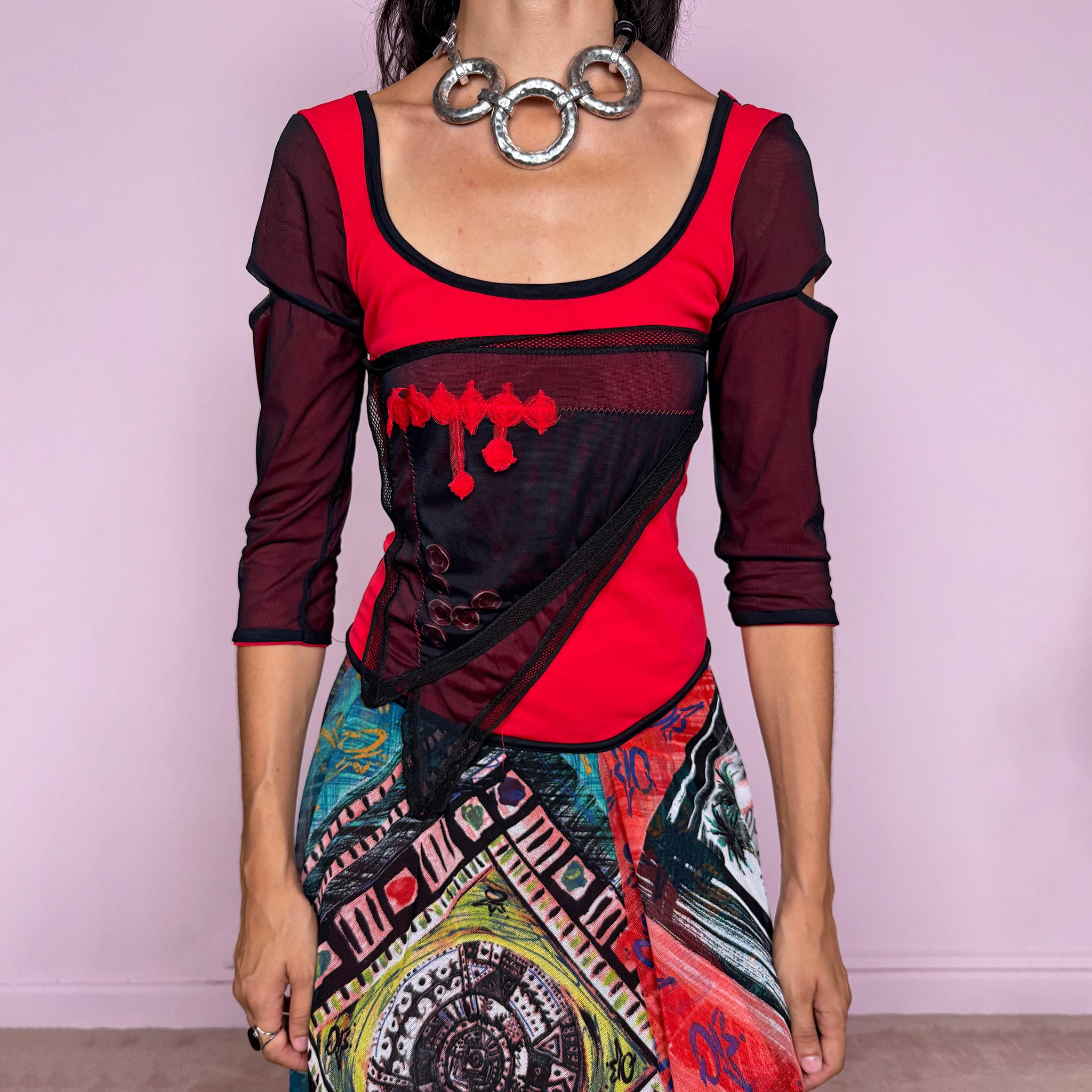 Vintage 2000s Save The Queen dress crafted from a stretchy semi-sheer mesh fabric with a bold graphic design. Designed in a fitted statement silhouette, it features a vivid red and black upper body with half sleeves and layered asymmetric panels that fall into a striking mixed-print skirt with abstract, geometric and hand-drawn motifs in red, turquoise, yellow, black and white tones. A highly visual Italian Y2K piece with an art-to-wear feel, perfect for a dramatic maximalist 2000s look.