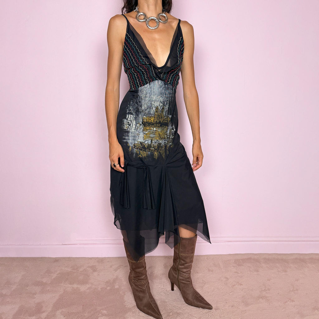 Vintage 2000s Save The Queen dress with semi-sheer mesh details and a sculptural asymmetric silhouette. Designed with thin straps, a deep V neckline, a fitted embroidered bodice with colorful zigzag stitching and a striking architectural graphic print across the front, falling into a layered black skirt with uneven sheer mesh panels and soft draped movement. A rare Italian Y2K statement piece with a dark romantic art-to-wear feel, balancing gothic fairycore