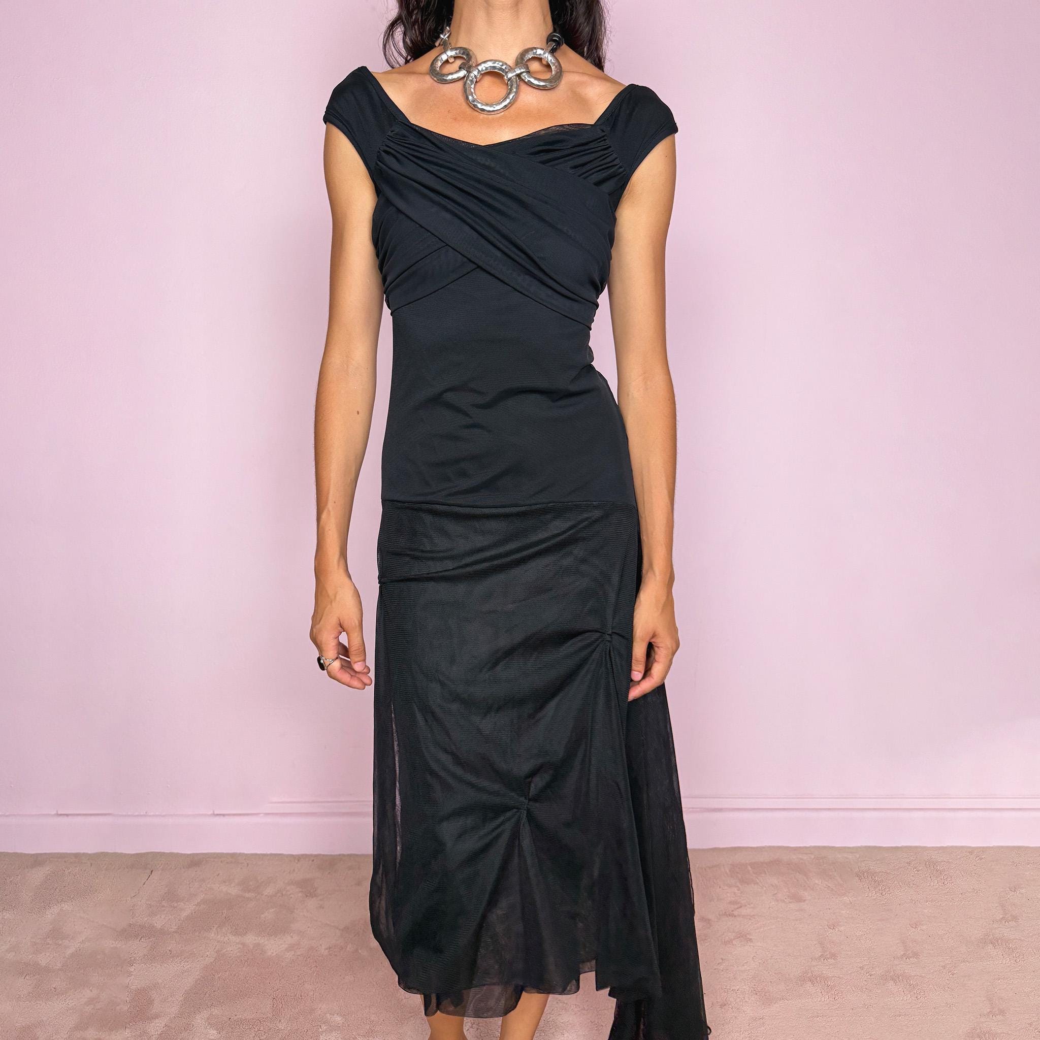 Vintage 2000s Save The Queen black midi dress with semi-sheer mesh layering and a sculptural asymmetric silhouette. It features a softly draped off-shoulder neckline, short cap sleeves, a fitted stretch body with diagonal ruching through the bust and waist, and an asymmetric layered skirt with sheer mesh panels, gathered details, and a long cascading side drape for dramatic movement. A rare Italian Y2K statement piece with a dark romantic evening feel, perfect for elegant parties and occasions.