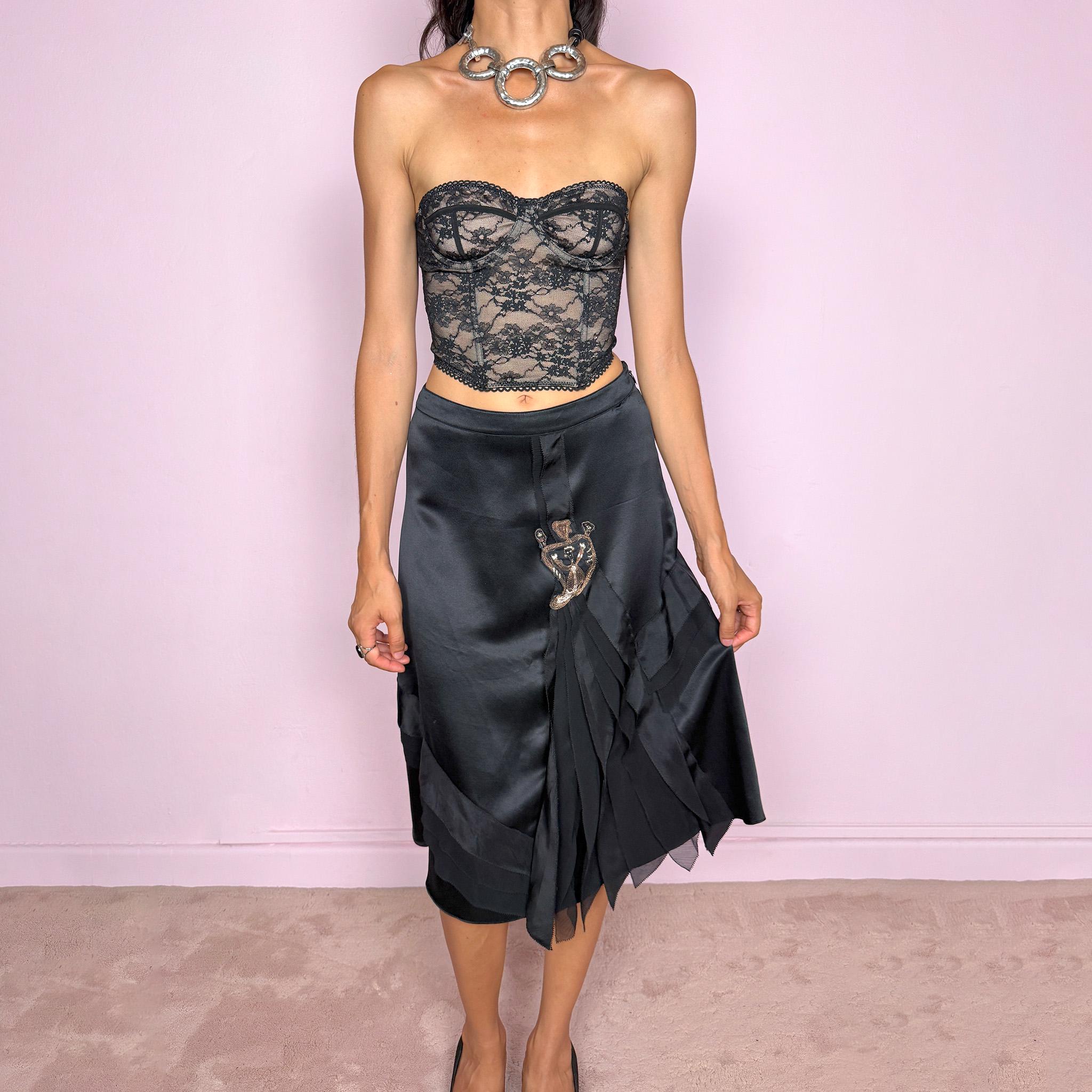 Vintage 2000s Kenzo black midi skirt crafted from 100% silk in a deep black satin finish, designed with a side zip closure and a structured no-stretch fit. It features a dramatic front detail with layered sheer pleated silk panels and an embroidered appliqué motif. A refined designer piece with a dark romantic evening feel, balancing minimal black silk with ornate Kenzo detailing. Can be worn high-waisted for size S, or slightly lower on the waist for XS and XXS. Excellent vintage condition.