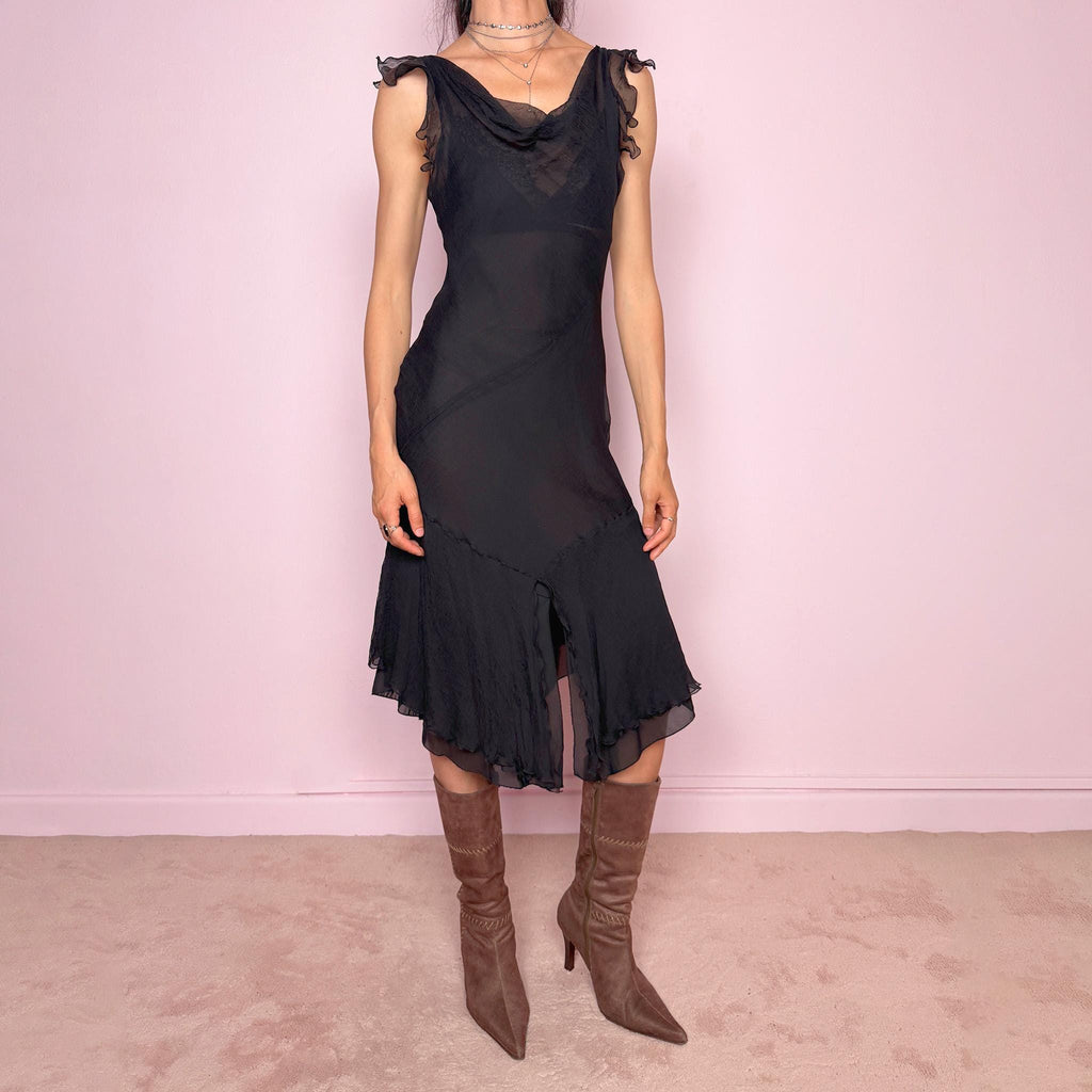 Vintage 2000s black midi dress with a romantic draped silhouette and semi-sheer layered construction. Designed with a cowl-style neckline, delicate ruffled cap sleeves, fitted waist, front slit detail, and fluid layered asymmetrical hem for an elegant dark evening look. The outer layer looks and feels like silk, but all labels are missing, so the exact fabric composition is unknown. Excellent vintage condition.