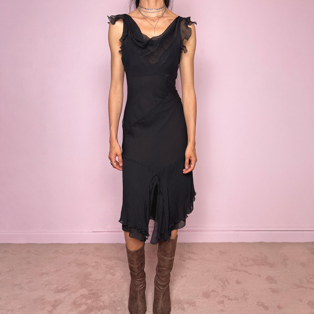 Vintage 2000s black midi dress with a romantic draped silhouette and semi-sheer layered construction. Designed with a cowl-style neckline, delicate ruffled cap sleeves, fitted waist, front slit detail, and fluid layered asymmetrical hem for an elegant dark evening look. The outer layer looks and feels like silk, but all labels are missing, so the exact fabric composition is unknown. Excellent vintage condition.
