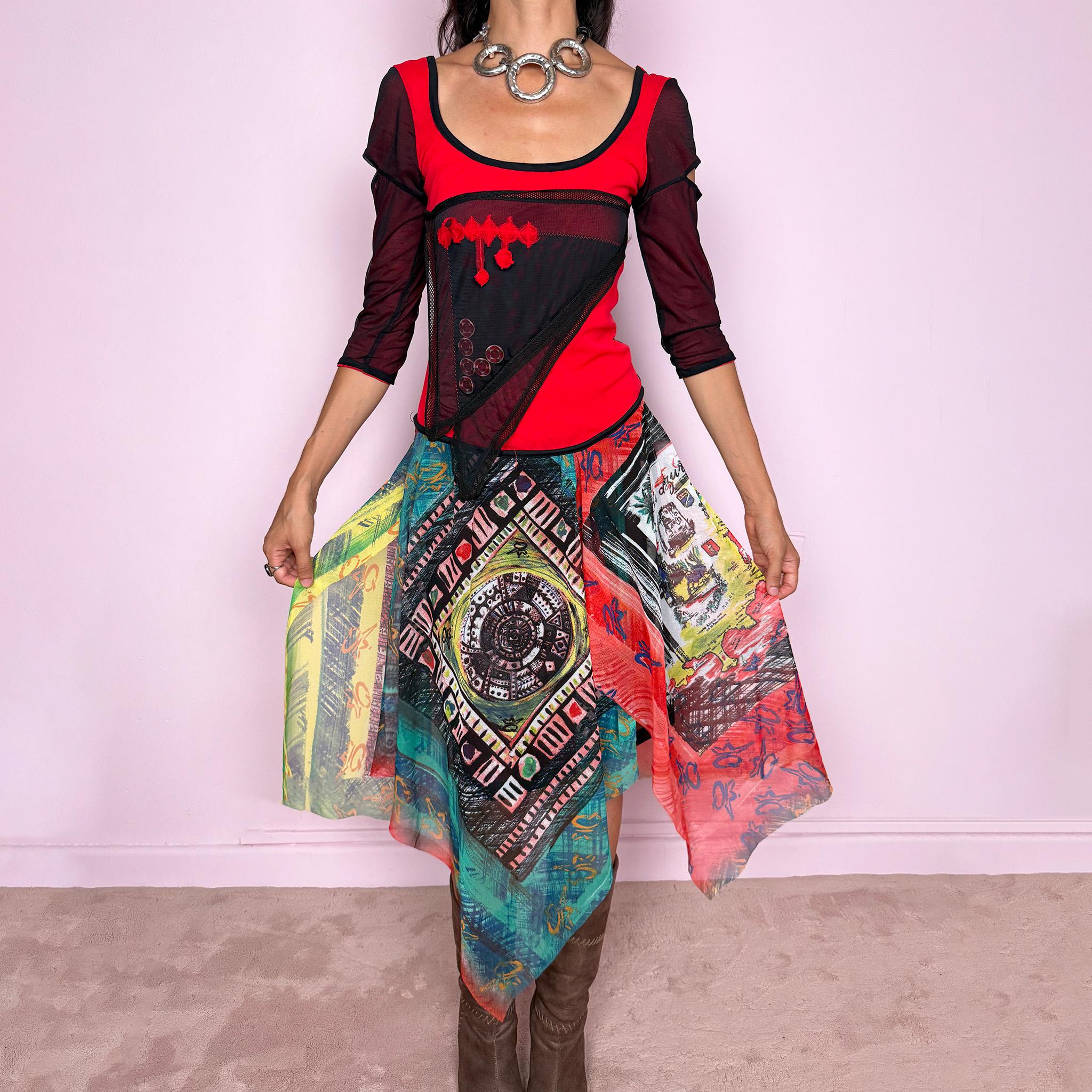 Vintage 2000s Save The Queen dress crafted from a stretchy semi-sheer mesh fabric with a bold graphic design. Designed in a fitted statement silhouette, it features a vivid red and black upper body with half sleeves and layered asymmetric panels that fall into a striking mixed-print skirt with abstract, geometric and hand-drawn motifs in red, turquoise, yellow, black and white tones. A highly visual Italian Y2K piece with an art-to-wear feel, perfect for a dramatic maximalist 2000s look.