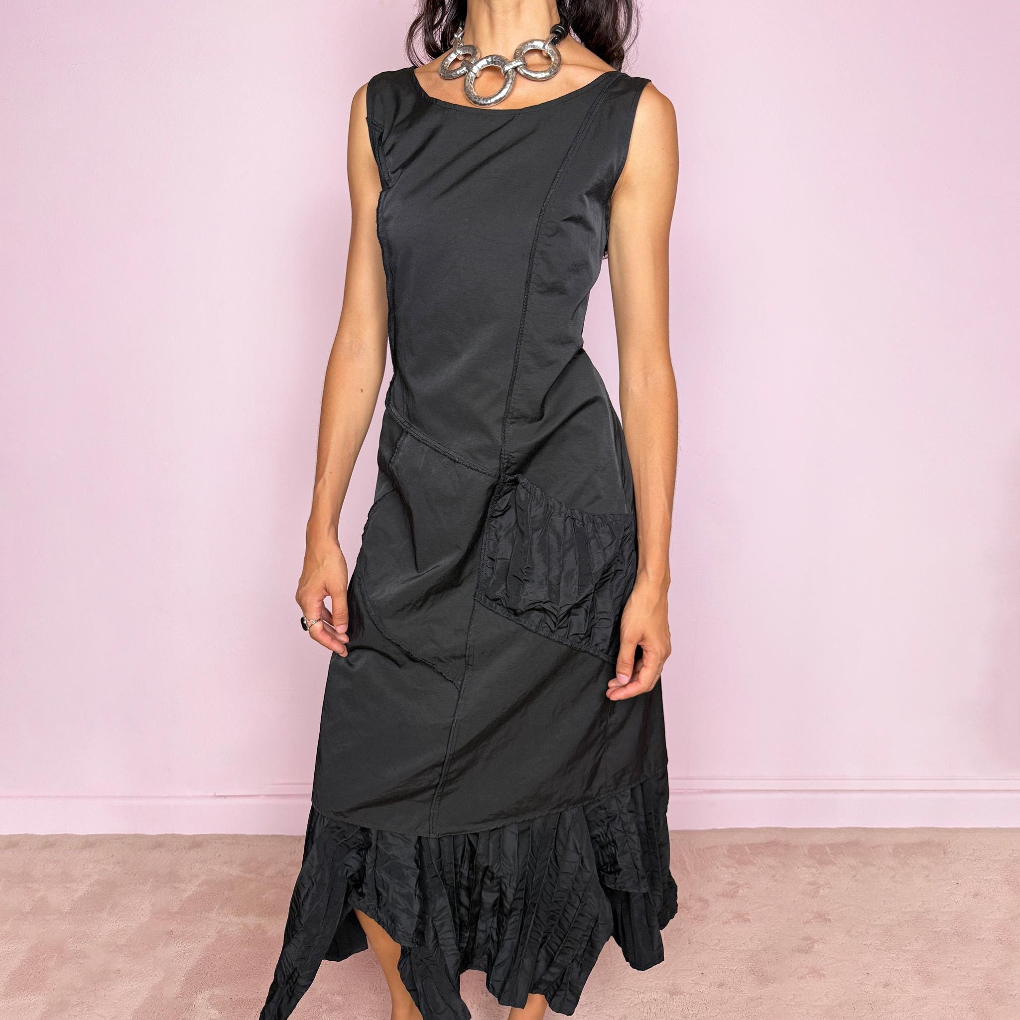 Vintage 2000s black midi dress designed in a structured no-stretch fabric with a side zip closure and an asymmetric panelled silhouette. It features a sleeveless scoop neckline, fitted upper body, diagonal seam construction, and an irregular ruffled hem with crinkled texture for sculptural movement. A dark romantic piece with an understated avant-garde feel, perfect for a minimal gothic look. Made by a French brand from 55% polyamide and 45% cotton, with a 100% polyester lining.