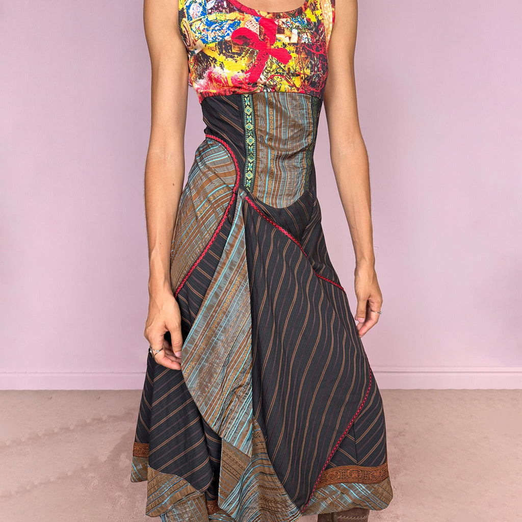 Vintage 2000s midi dress designed with a dramatic medieval-inspired avant-garde silhouette. It features a graphic bust panel with vivid abstract artwork, a fitted corset-effect waist with striped and patterned panels, a side zip closure, and a flowing asymmetric skirt with mixed striped fabrics, contrast trims, and layered draped sections for sculptural movement. Only the bust area has stretch, while the rest of the dress  A rare fantasy statement piece with a theatrical baroque feel.