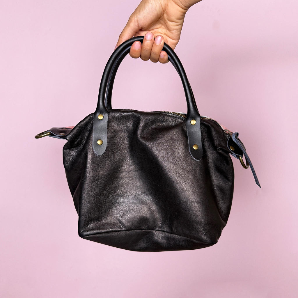 Vintage 2000s handbag, made in Italy from real leather, designed with a soft pink hair-on leather front panel and a contrasting black leather back for a playful two-tone finish. It features double black top handles, brass-tone hardware, a top zip closure, and a removable crossbody strap for versatile wear as a handbag, shoulder bag, or crossbody. A fun Y2K pastel bag. Excellent vintage condition.