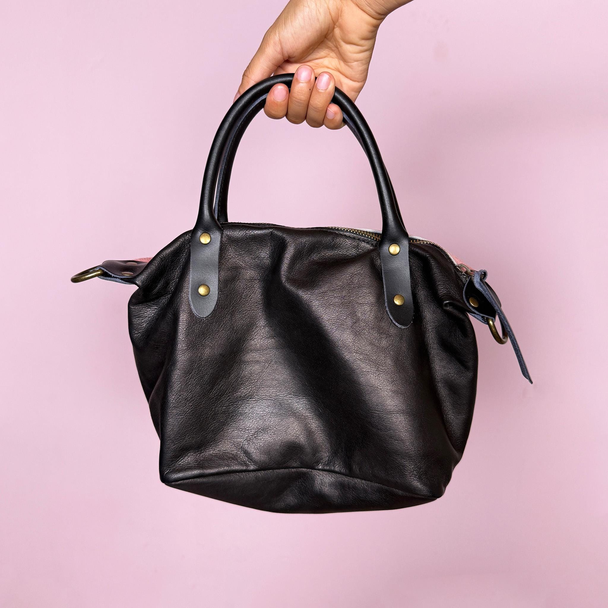 Vintage 2000s handbag, made in Italy from real leather, designed with a soft pink hair-on leather front panel and a contrasting black leather back for a playful two-tone finish. It features double black top handles, brass-tone hardware, a top zip closure, and a removable crossbody strap for versatile wear as a handbag, shoulder bag, or crossbody. A fun Y2K pastel bag. Excellent vintage condition.