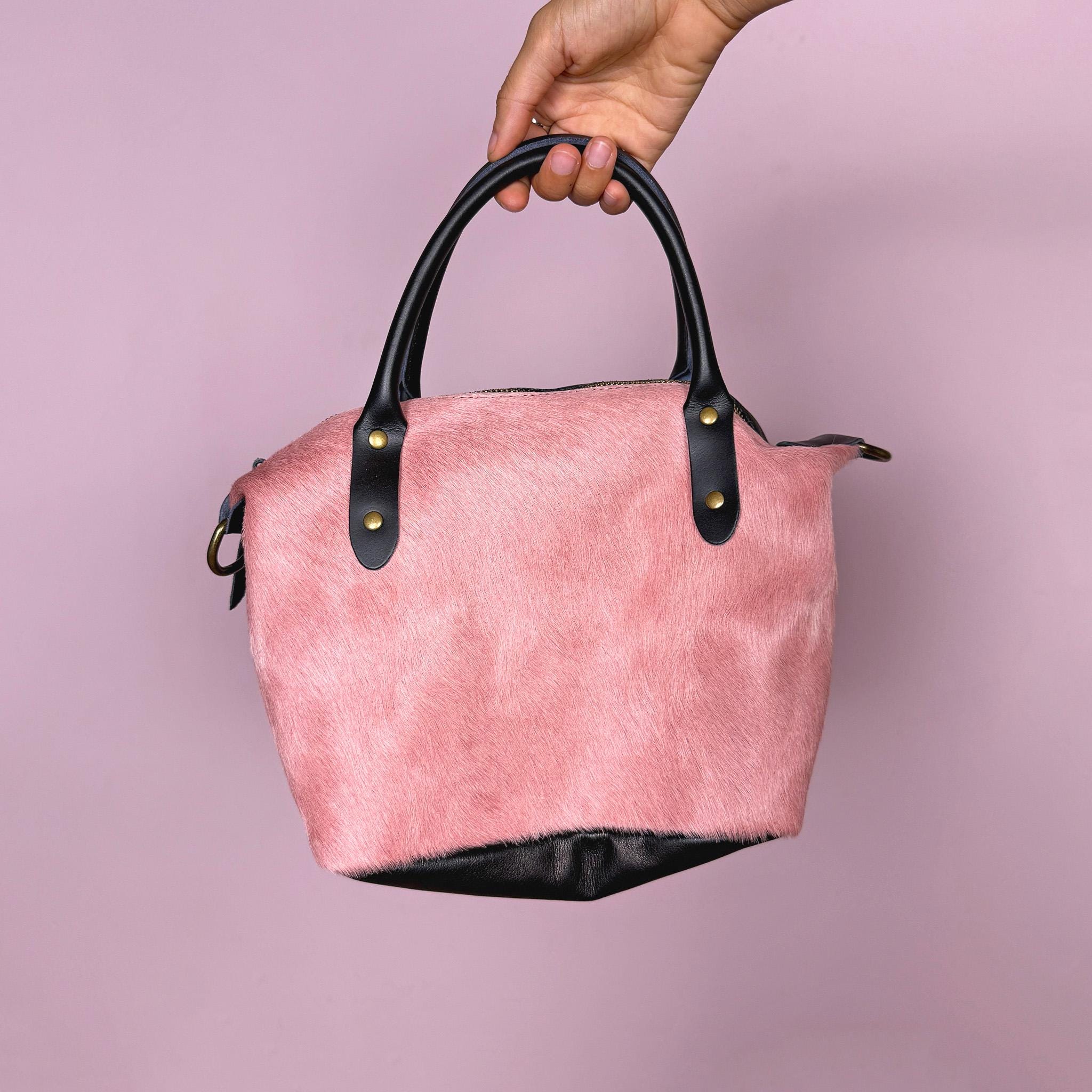 Vintage 2000s handbag, made in Italy from real leather, designed with a soft pink hair-on leather front panel and a contrasting black leather back for a playful two-tone finish. It features double black top handles, brass-tone hardware, a top zip closure, and a removable crossbody strap for versatile wear as a handbag, shoulder bag, or crossbody. A fun Y2K pastel bag. Excellent vintage condition.