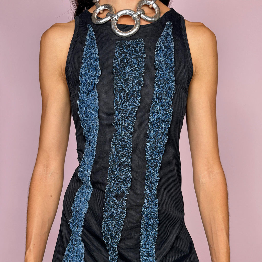 Vintage 2000s maxi dress crafted from stretchy black mesh with a fitted sleeveless silhouette, a semi-sheer outer layer, and an asymmetric flowing hem. Detailed with contrasting blue embroidered threadwork running vertically across the body, creating a textured effect with a distinctly avant-garde Y2K feel. Made in Italy by an Italian brand from 100% polyamide. Excellent vintage condition.
