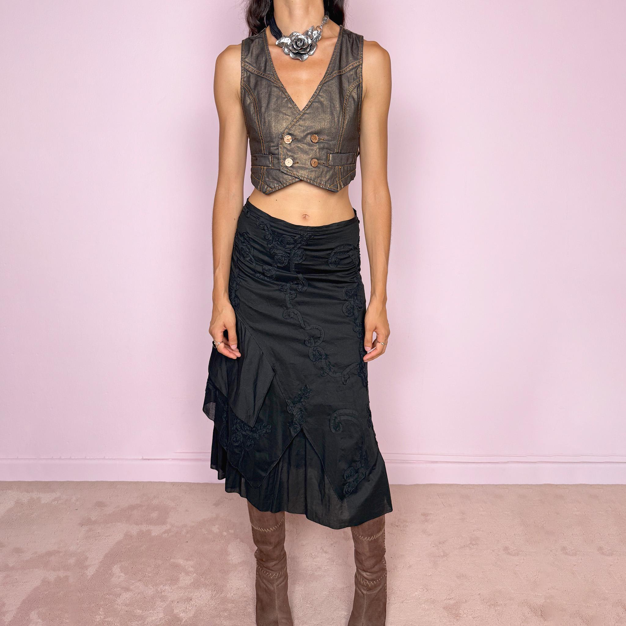 Vintage 2000s black midi skirt crafted from 100% cotton with layered asymmetric panels and tonal floral embroidery appliqué. Features a back zip closure and no stretch. Ideal for bohemian, dark fairy, or summer styling. Can be worn high-waisted for size S or slightly lower on the waist for sizes XS–XXS. Made in France by a French brand and fully lined in 100% polyester. Excellent vintage condition.