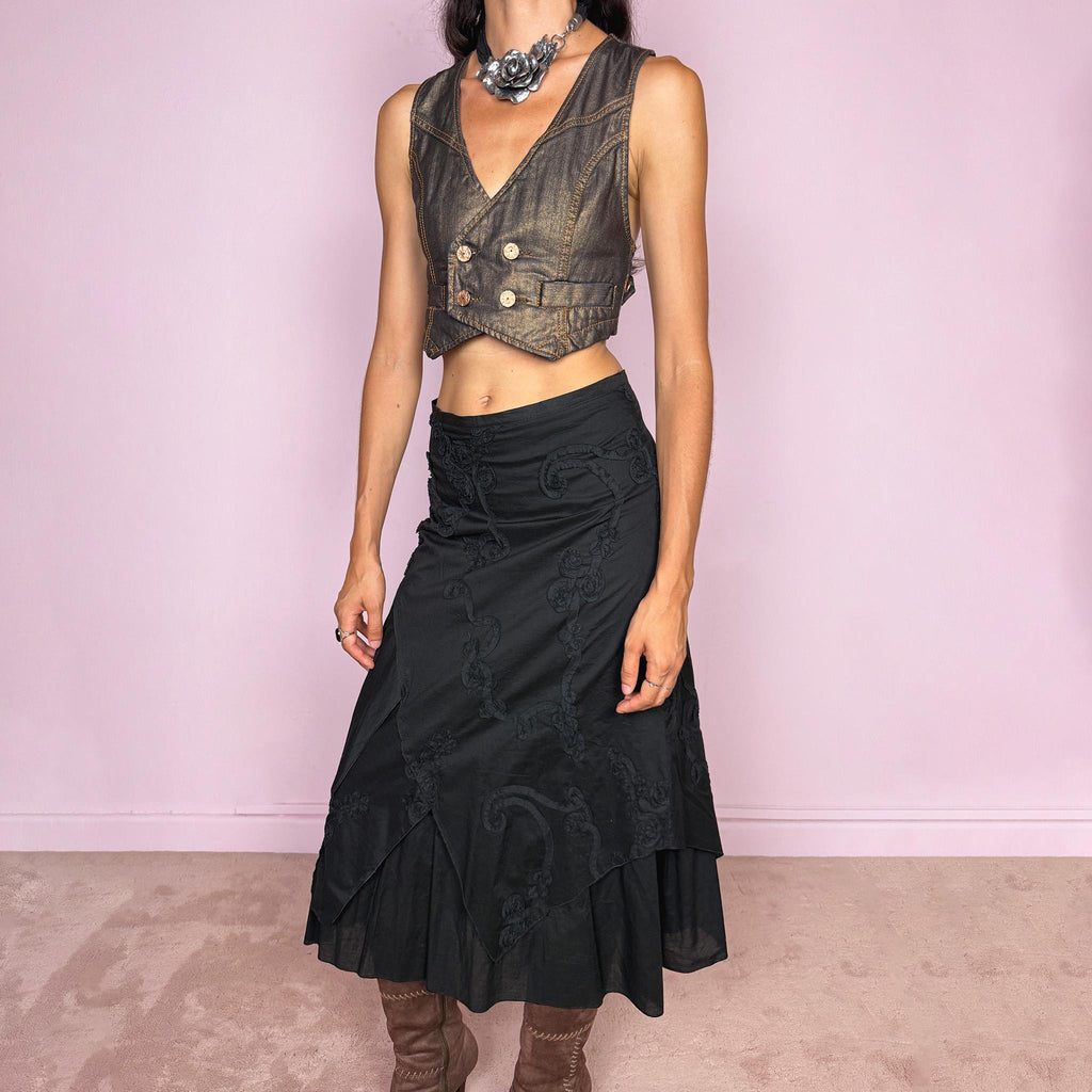 Vintage 2000s black midi skirt crafted from 100% cotton with layered asymmetric panels and tonal floral embroidery appliqué. Features a back zip closure and no stretch. Ideal for bohemian, dark fairy, or summer styling. Can be worn high-waisted for size S or slightly lower on the waist for sizes XS–XXS. Made in France by a French brand and fully lined in 100% polyester. Excellent vintage condition.