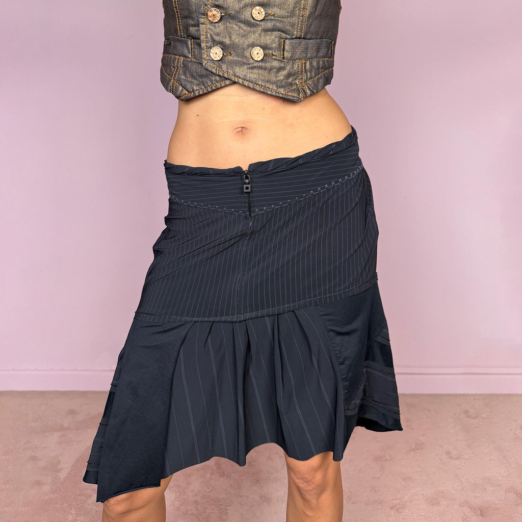 Vintage 2000s Marithé + François Girbaud asymmetric skirt in black and deep navy, featuring a deconstructed patchwork construction that combines fine pinstripes with contrasting smooth panels, a front zip closure, curved seam detailing, and softly pleated sections that create volume and irregular movement through the hem. Can be worn high-waisted for size M or lower-rise for size S. Made from a stretchy polyamide, elastane, and cotton blend. Excellent vintage condition.