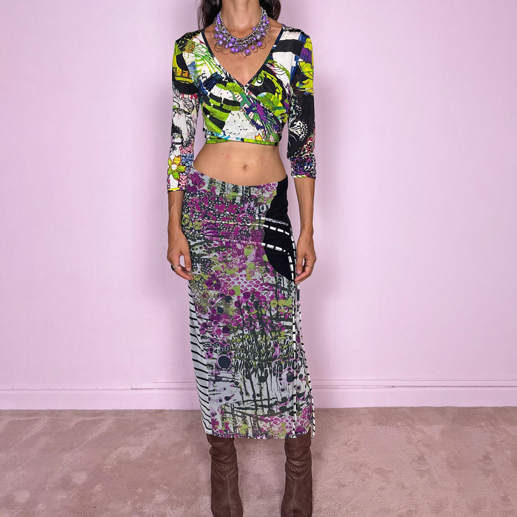 Vintage 2000s two-piece set featuring a fitted wrap-style crop top and matching printed midi skirt. The top has three-quarter sleeves, a deep V-neckline, and an adjustable tie-back closure. The matching skirt is made from stretchy mesh with an elasticated waist and abstract graphic print, featuring ruched detailing through the hip and decorative trailing straps for an asymmetric, deconstructed finish. It can be worn mid- to low-rise.