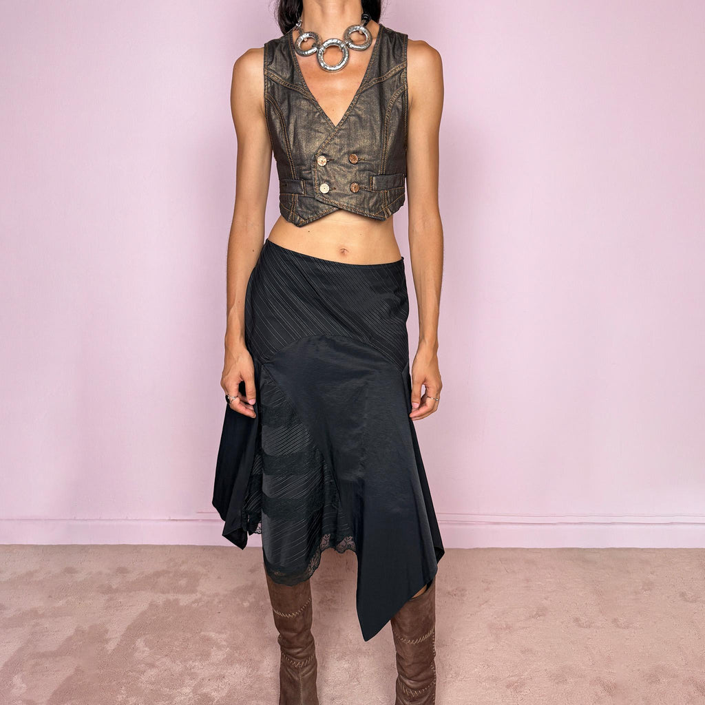 Vintage 2000s black asymmetric midi skirt featuring a deconstructed patchwork construction that combines fine pinstripe panels with contrasting fabric sections and subtle lace-trim detailing. Designed with a dramatic irregular handkerchief-style hem and a dark avant-garde Y2K silhouette. Features a side zip closure and no stretch. Can be worn high-waisted for size M or mid- to lower-rise for sizes S–XS.