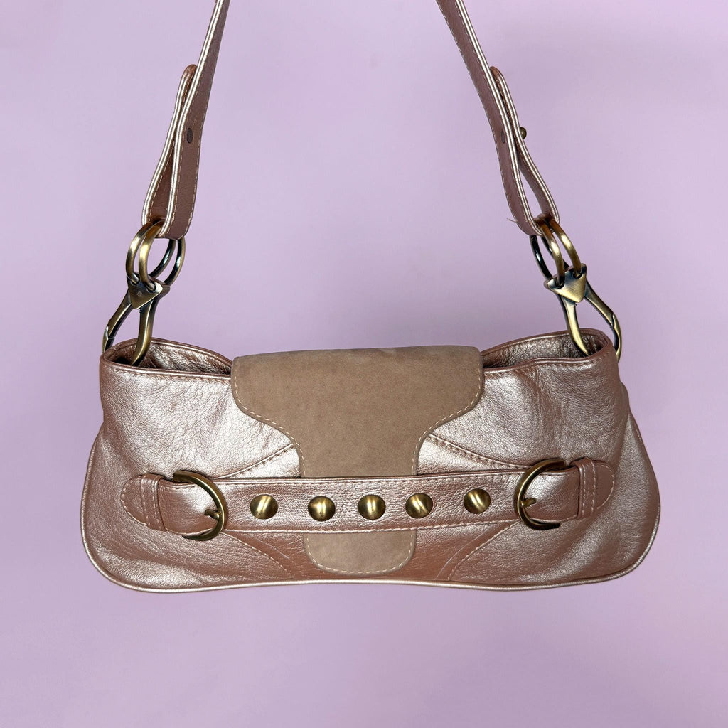 Vintage 2000s shoulder bag made in Italy in a beautiful metallic bronze-taupe shade with warm golden undertones. Designed with a baguette silhouette, statement buckle-inspired front detailing with antique brass-tone hardware, a shoulder strap, and a suede front flap. Finished with a zip-top closure. The interior label states "Genuine Leather". Excellent vintage condition.