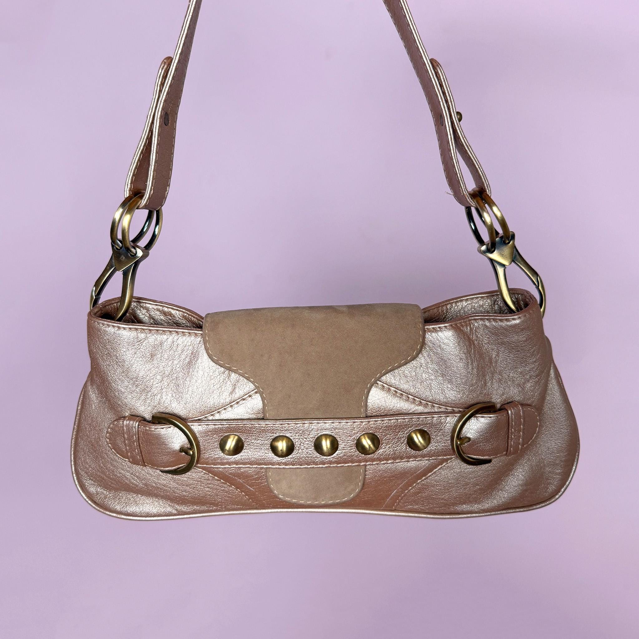 Vintage 2000s shoulder bag made in Italy in a beautiful metallic bronze-taupe shade with warm golden undertones. Designed with a baguette silhouette, statement buckle-inspired front detailing with antique brass-tone hardware, a shoulder strap, and a suede front flap. Finished with a zip-top closure. The interior label states "Genuine Leather". Excellent vintage condition.
