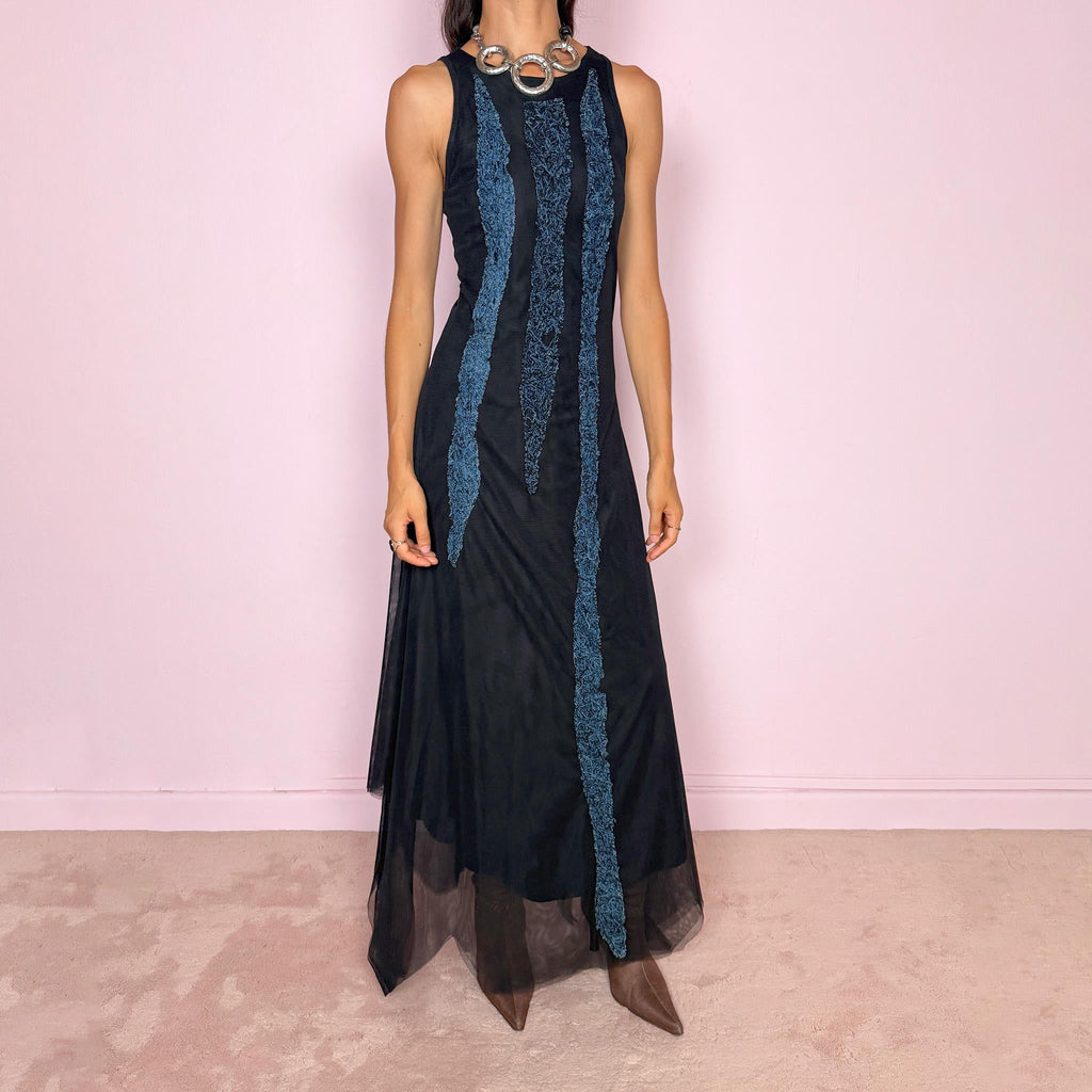 Vintage 2000s maxi dress crafted from stretchy black mesh with a fitted sleeveless silhouette, a semi-sheer outer layer, and an asymmetric flowing hem. Detailed with contrasting blue embroidered threadwork running vertically across the body, creating a textured effect with a distinctly avant-garde Y2K feel. Made in Italy by an Italian brand from 100% polyamide. Excellent vintage condition.