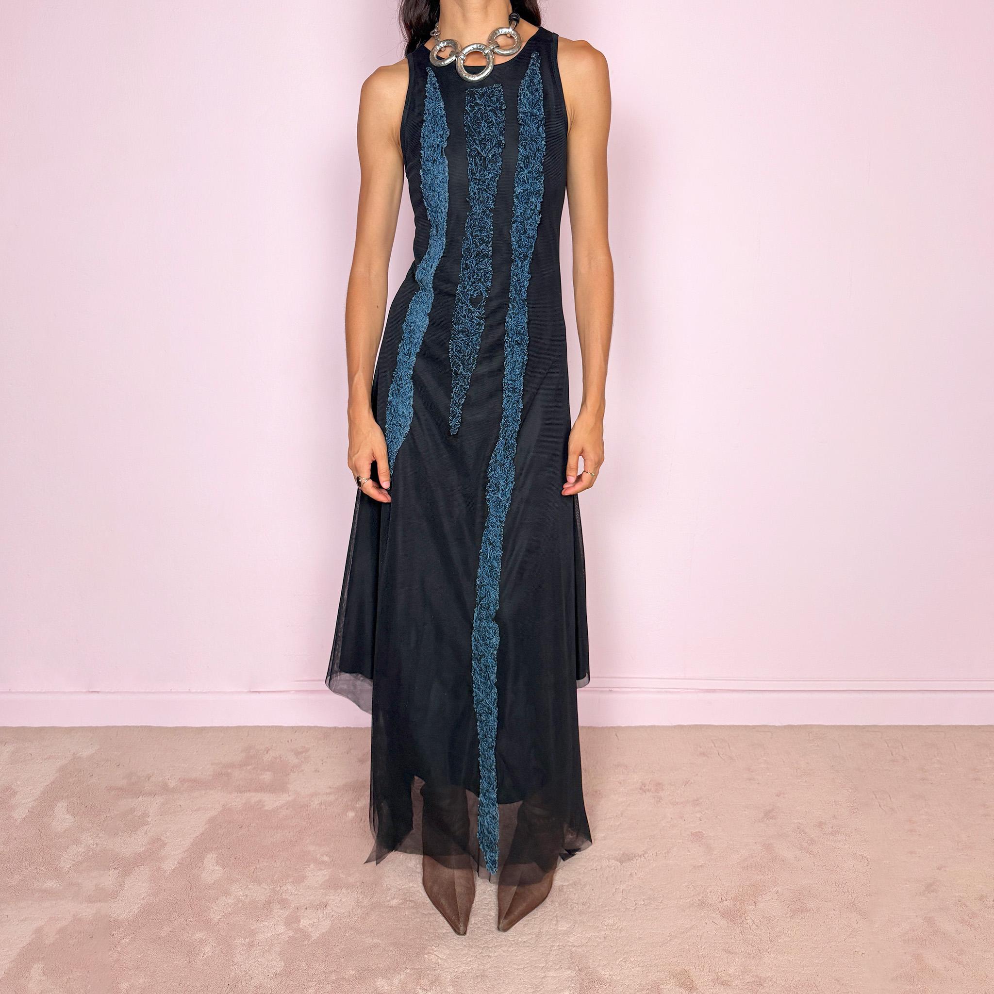 Vintage 2000s maxi dress crafted from stretchy black mesh with a fitted sleeveless silhouette, a semi-sheer outer layer, and an asymmetric flowing hem. Detailed with contrasting blue embroidered threadwork running vertically across the body, creating a textured effect with a distinctly avant-garde Y2K feel. Made in Italy by an Italian brand from 100% polyamide. Excellent vintage condition.