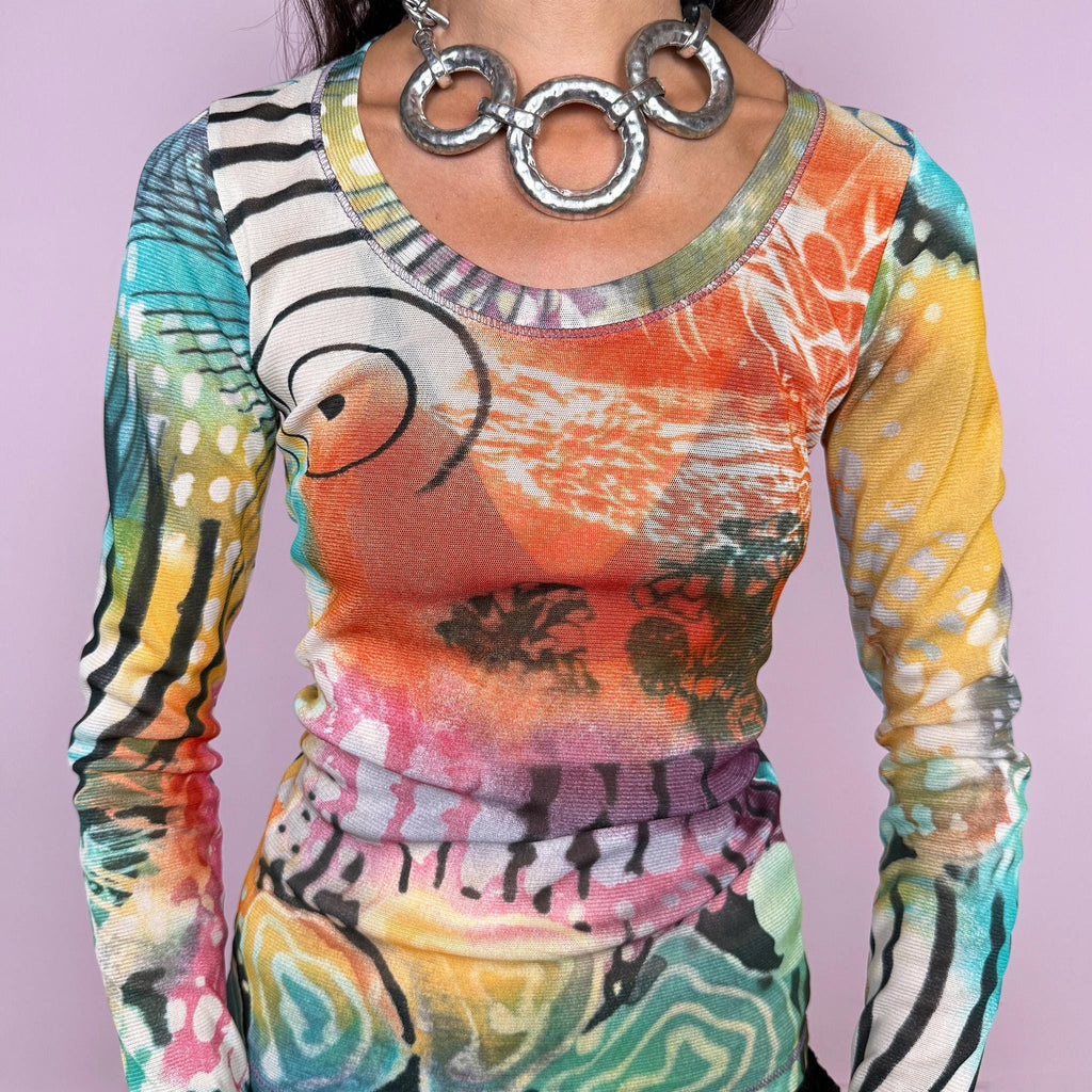 Vintage 2000s long-sleeve mesh top featuring a vibrant abstract graphic print mixing turquoise, orange, yellow, pink, and green with contrasting organic, striped, and painterly motifs. Designed with a fitted silhouette, scoop neckline, and semi-sheer lightweight mesh construction. Stretchy fabric creates a close, second-skin fit. A strong maximalist Y2K piece with an art-print feel. Made in France by a French brand from 100% polyester. Excellent vintage condition.