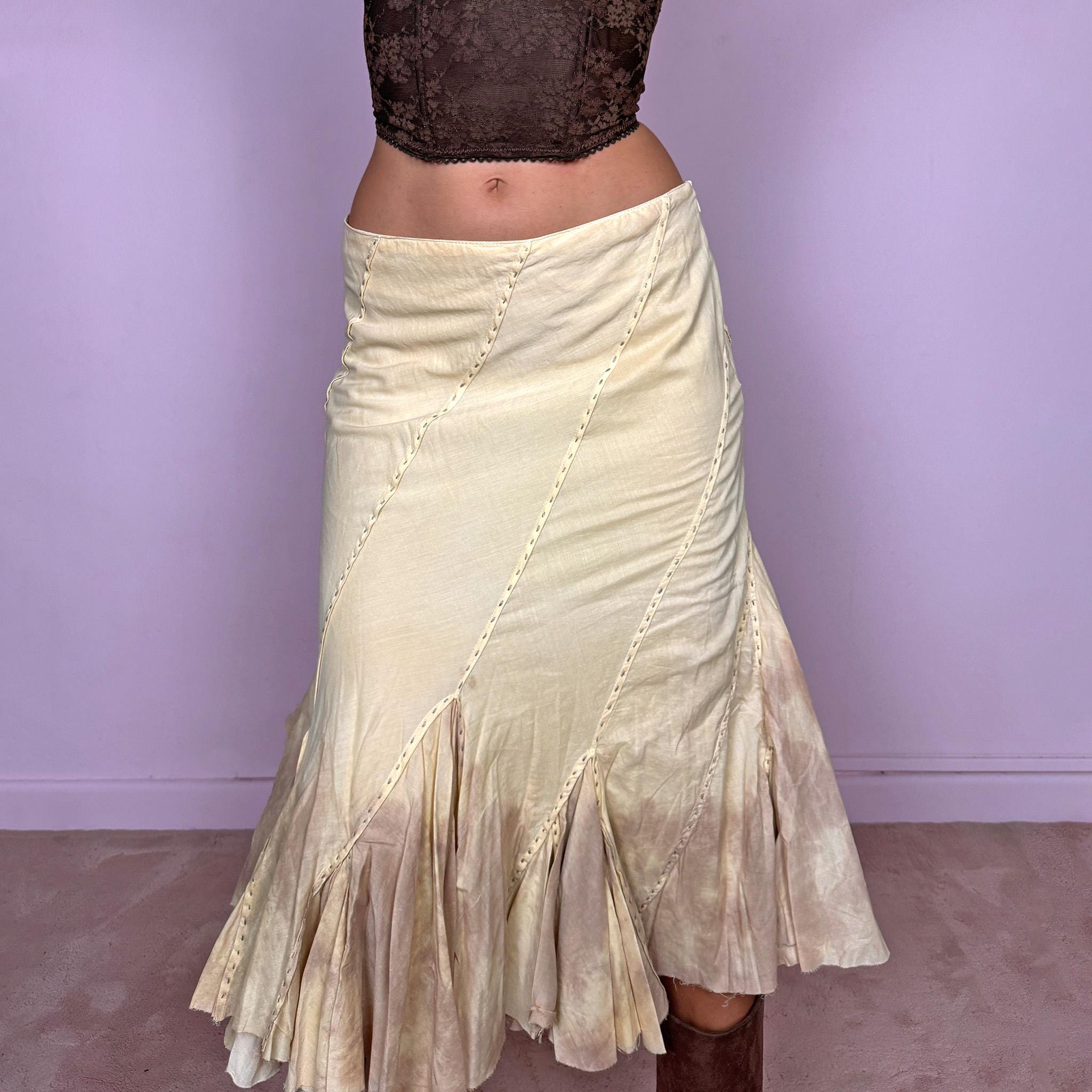 Vintage 2000s light yellow asymmetric midi skirt with a romantic, deconstructed silhouette, featuring curved diagonal paneling, visible contrast stitching, and flared godet inserts. Finished with a tie-dye effect concentrated around the lower panels and raw hem. Non-stretch fabric with a side zip closure. Can be worn mid-rise for size S or lower-rise for size XS. Ideal for bohemian, fairy-inspired, earthy, rustic, and organic summer styling.