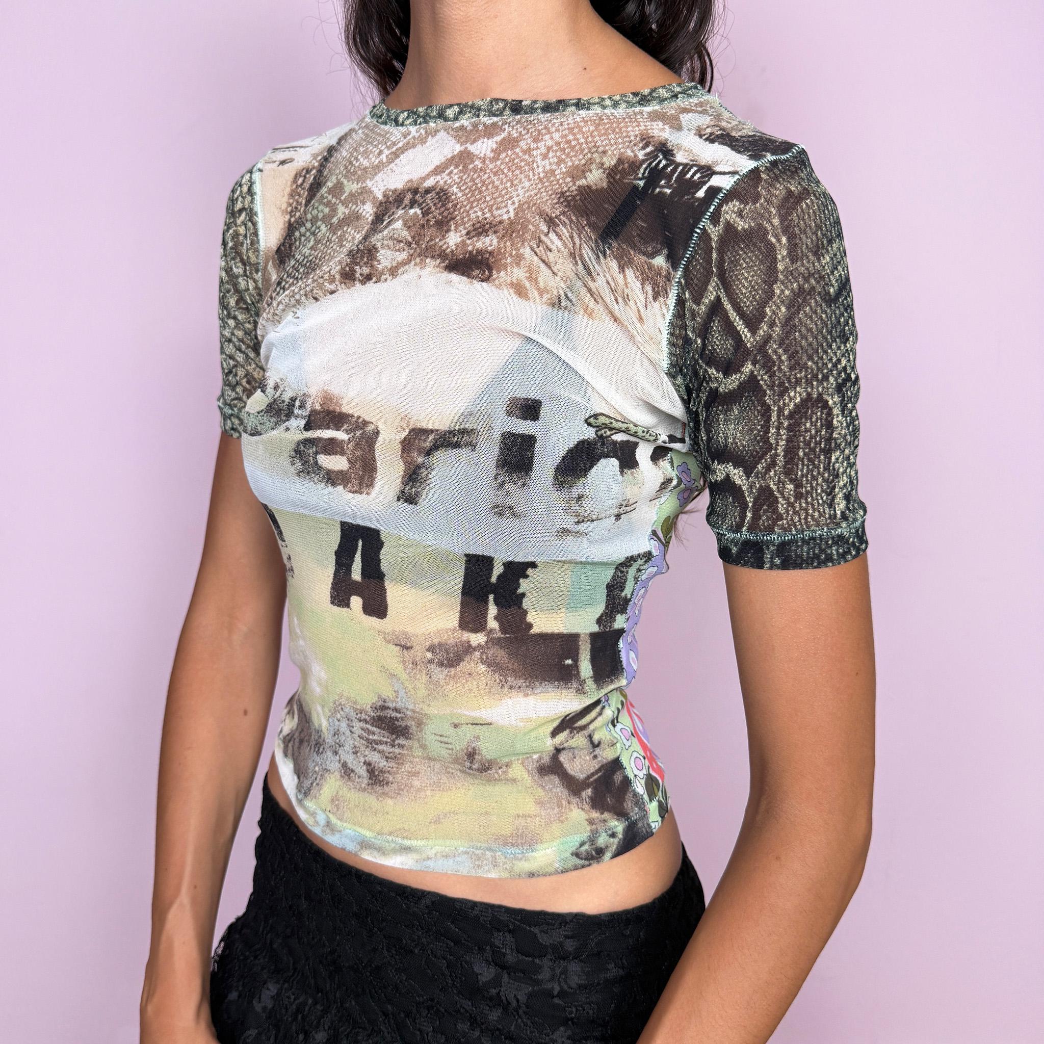 Vintage 2000s Roberto Cavalli Freedom mesh top crafted from semi-sheer, stretchy mesh with a fitted silhouette and short sleeves. It features an eclectic mixed print that contrasts earthy photographic and snakeskin-inspired graphics at the front with a vibrant retro floral print across the back. Lightweight, sheer, and body-skimming, with a distinctly maximalist Y2K Cavalli feel. Made in Italy from 100% polyamide. Excellent vintage condition.