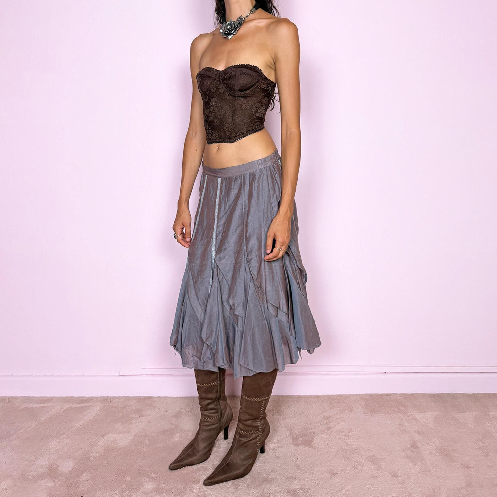 Vintage 2000s bluish-gray iridescent midi skirt featuring a subtle sheen that shifts between dusty blue, gray, and muted mauve tones. Designed with a fluid asymmetric layered construction, curved paneling, delicate lace-trim inserts, and an irregular hem that creates soft movement and a deconstructed silhouette. Perfect for delicate, ethereal styling. Features a back zip closure and no stretch. Can be worn high-waisted for size M or lower-rise for sizes XS–S. Made from 70% cotton and 30% silk