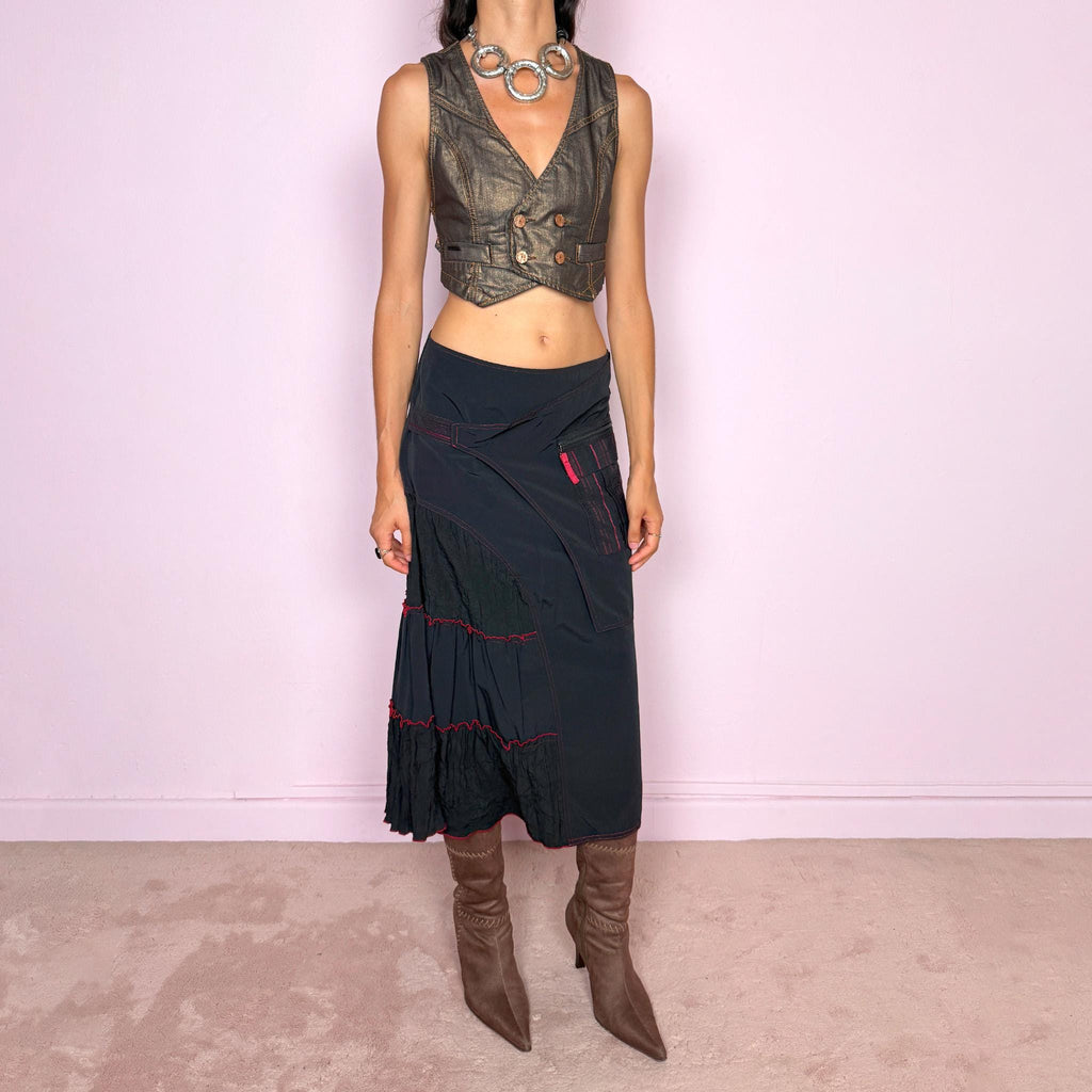 Vintage 2000s black deconstructed midi skirt with a structured, non-stretch feel. Features asymmetric paneled construction, contrasting red topstitching, a utility-inspired zip pocket, and layered crinkled fabric inserts. Finished with a back zip closure. A distinctive dark avant-garde piece with a dystopian, futuristic Y2K feel. Can be worn high-waisted for size M or mid- to lower-rise for sizes S–XS. Made in France by a French brand.