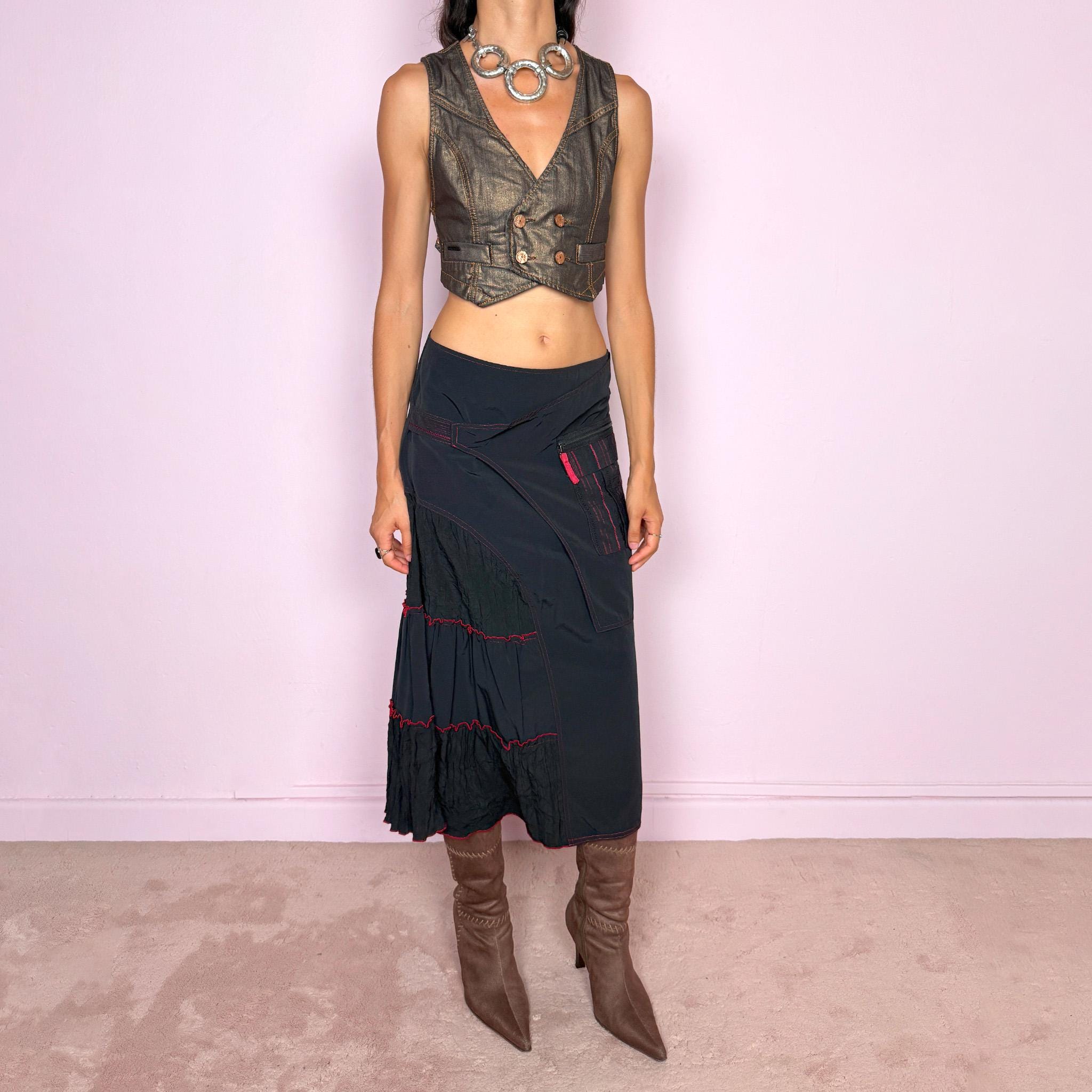 Vintage 2000s black deconstructed midi skirt with a structured, non-stretch feel. Features asymmetric paneled construction, contrasting red topstitching, a utility-inspired zip pocket, and layered crinkled fabric inserts. Finished with a back zip closure. A distinctive dark avant-garde piece with a dystopian, futuristic Y2K feel. Can be worn high-waisted for size M or mid- to lower-rise for sizes S–XS. Made in France by a French brand.