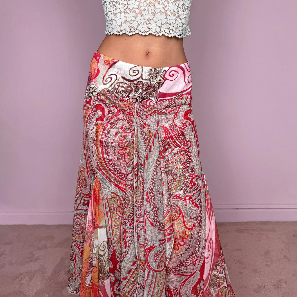 Vintage 2000s 100% silk midi skirt featuring a richly layered red, pink, and earthy-toned paisley and abstract print. The design combines a printed underlayer with a semi-sheer silk overlay, creating depth and movement as the two patterns interact. Cut with multiple godet inserts for a fluid flared silhouette and softly asymmetric hem, giving the skirt a romantic maximalist, art-to-wear feel. Non-stretch with a back zip closure. Can be worn mid-rise for size S or lower on the waist for size XS.