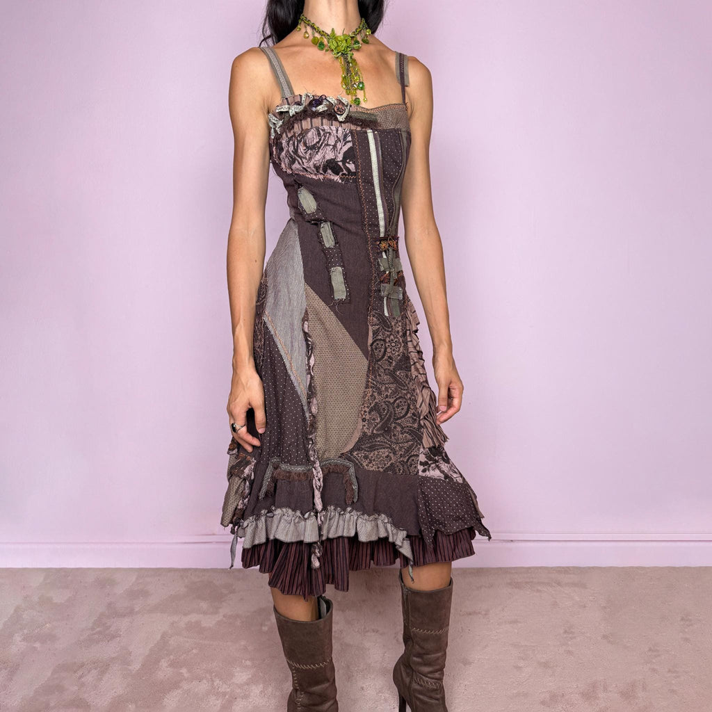 Vintage 2000s deconstructed midi dress with a distinctive rag-doll-inspired patchwork construction in brown, khaki green, mauve, and gray tones. Featuring mixed patterned panels, exposed raw-edge seams, contrast stitching, ribbon and buckle details, gathered ruffles, and an irregular layered hem for a highly textured avant-garde silhouette. Designed with adjustable shoulder straps, a shirred elastic back for flexibility, and a side zip closure.