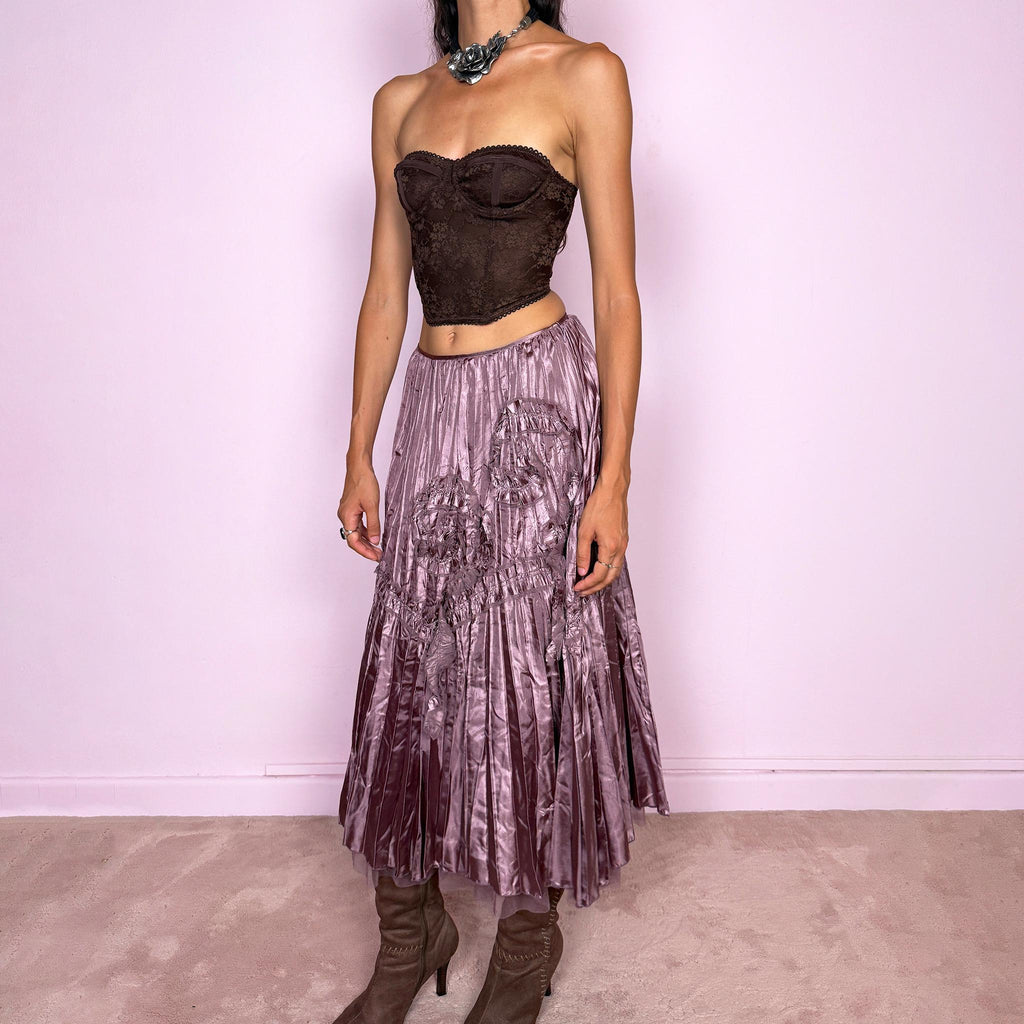 Vintage 2000s dusty mauve metallic midi skirt featuring intricate all-over pleating with a fluid iridescent sheen, sculptural floral appliqué details, and sheer tulle fabric peeking from underneath the hem. Ideal for parties or dreamy, romantic elevated outfits. Can be worn high-waisted for size S or lower on the waist for size XS. From a French brand. Crafted from 100% polyester with no stretch and finished with a side zip closure. Excellent vintage condition.