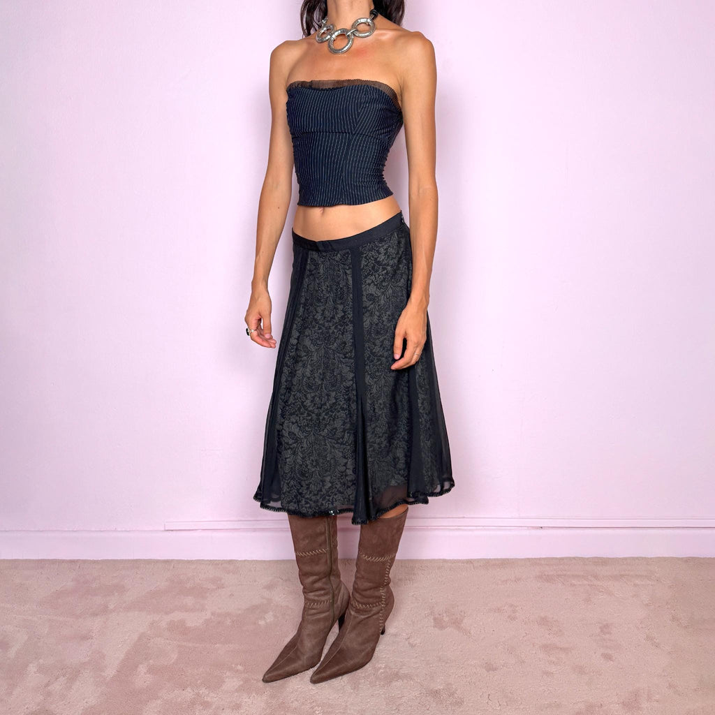Vintage 2000s black silk A-line flared midi skirt crafted from 100% silk, with contrasting beige and black lining that subtly reveals an intricate dark floral paisley pattern through the outer fabric, a semi-sheer black overlay, and delicate black sequin trim along the edge. Elegant with a romantic eveningwear feel. Non-stretch with a side zip closure. Can be worn mid-rise for size M or lower-rise for size S. From a German brand. Excellent vintage condition.