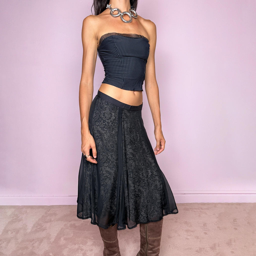 Vintage 2000s black silk A-line flared midi skirt crafted from 100% silk, with contrasting beige and black lining that subtly reveals an intricate dark floral paisley pattern through the outer fabric, a semi-sheer black overlay, and delicate black sequin trim along the edge. Elegant with a romantic eveningwear feel. Non-stretch with a side zip closure. Can be worn mid-rise for size M or lower-rise for size S. From a German brand. Excellent vintage condition.
