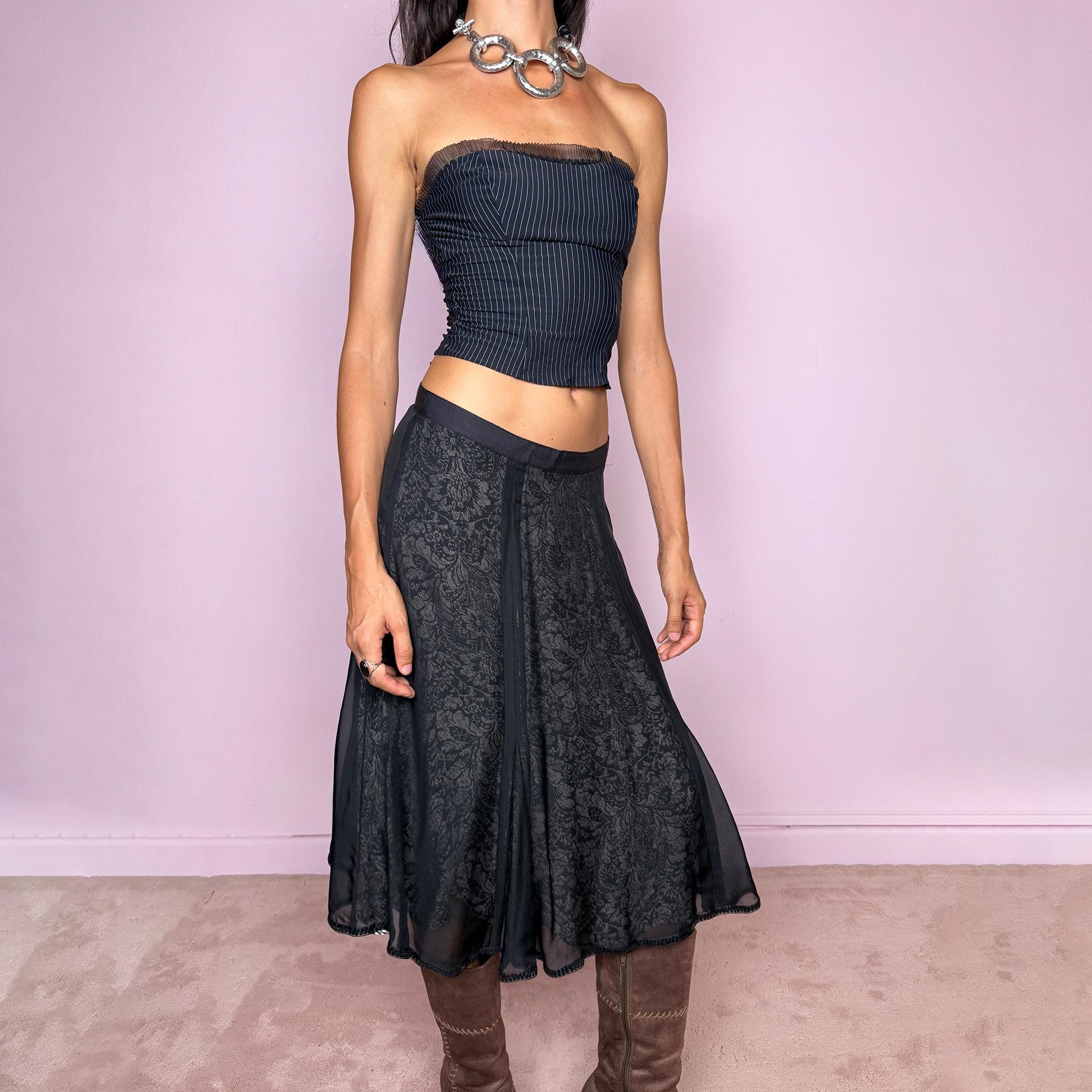 Vintage 2000s black silk A-line flared midi skirt crafted from 100% silk, with contrasting beige and black lining that subtly reveals an intricate dark floral paisley pattern through the outer fabric, a semi-sheer black overlay, and delicate black sequin trim along the edge. Elegant with a romantic eveningwear feel. Non-stretch with a side zip closure. Can be worn mid-rise for size M or lower-rise for size S. From a German brand. Excellent vintage condition.