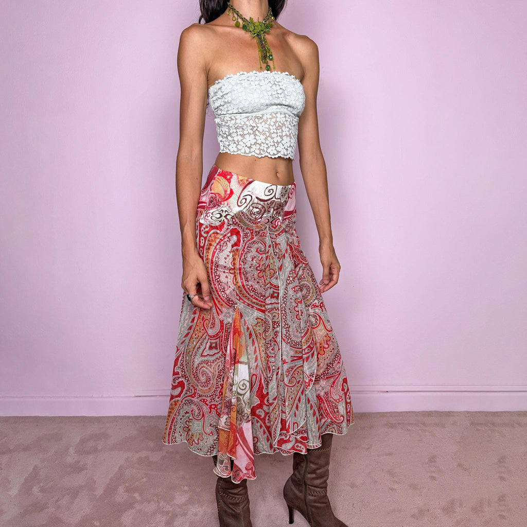 Vintage 2000s 100% silk midi skirt featuring a richly layered red, pink, and earthy-toned paisley and abstract print. The design combines a printed underlayer with a semi-sheer silk overlay, creating depth and movement as the two patterns interact. Cut with multiple godet inserts for a fluid flared silhouette and softly asymmetric hem, giving the skirt a romantic maximalist, art-to-wear feel. Non-stretch with a back zip closure. Can be worn mid-rise for size S or lower on the waist for size XS.