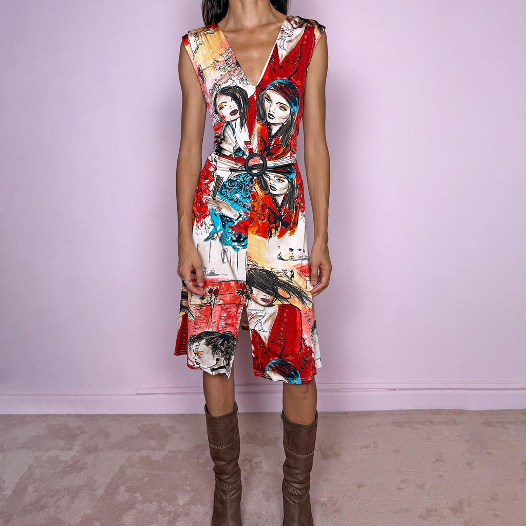 Vintage 2000s graphic midi dress by Canadian designer Joseph Ribkoff, made in Canada from a stretchy fabric with a fluid, body-skimming fit. Featuring a bold illustrated art print in red, blue, black, and cream, with stylized female figures and sketch-like graphics throughout. Designed with a deep V-neckline, sleeveless cut, front slit, and a circular buckle detail at the waist that creates draping through the front. A striking maximalist art-to-wear piece. Excellent vintage condition.