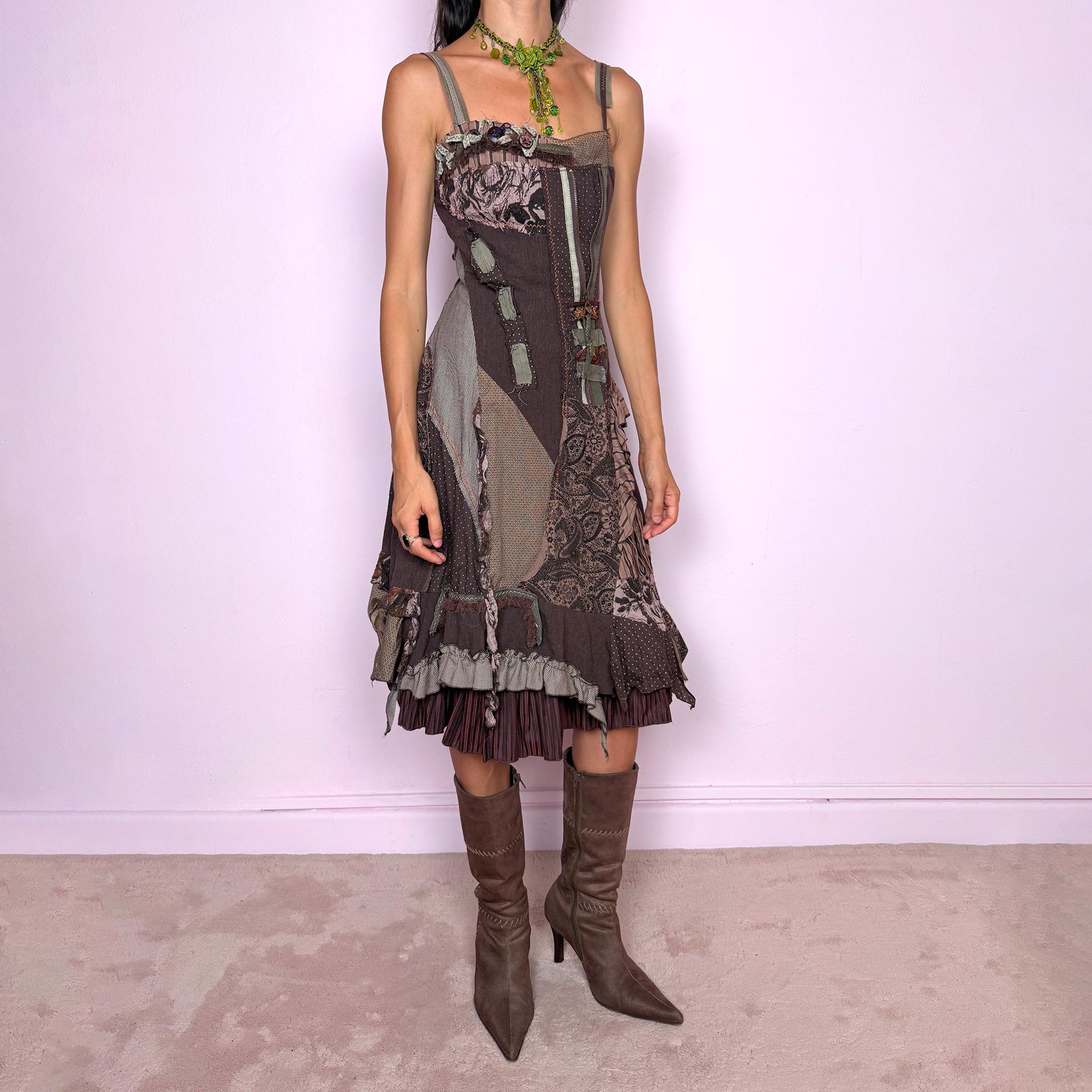 Vintage 2000s deconstructed midi dress with a distinctive rag-doll-inspired patchwork construction in brown, khaki green, mauve, and gray tones. Featuring mixed patterned panels, exposed raw-edge seams, contrast stitching, ribbon and buckle details, gathered ruffles, and an irregular layered hem for a highly textured avant-garde silhouette. Designed with adjustable shoulder straps, a shirred elastic back for flexibility, and a side zip closure.