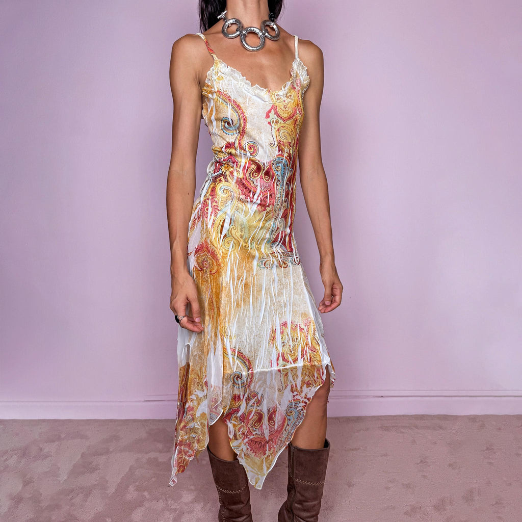 Vintage 2000s asymmetrical handkerchief-hem slip midi dress featuring a richly layered paisley-inspired graphic print in yellow, cream, gold, rust, terracotta, and blue tones, with thin straps, a ruffled neckline, and an irregular pointed hem that creates fluid movement. The fitted silhouette and distressed painterly print give it a distinctly Y2K maximalist, bohemian festival feel. Made in France from stretchy 100% polyester. Excellent vintage condition.