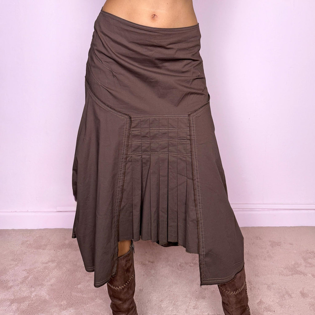Vintage 2000s brown asymmetric midi skirt featuring a draped construction, contrast topstitching, and a sculptural asymmetric hem with pleated panel detailing at the front. Finished with a back zip closure. The earthy brown tone and deconstructed tailoring give it a distinctly avant-garde aesthetic. Can be worn mid-rise for size S or lower on the waist for size XS. From a French brand, made in France from a slightly stretchy 96% cotton and 4% elastane blend. Excellent vintage condition.