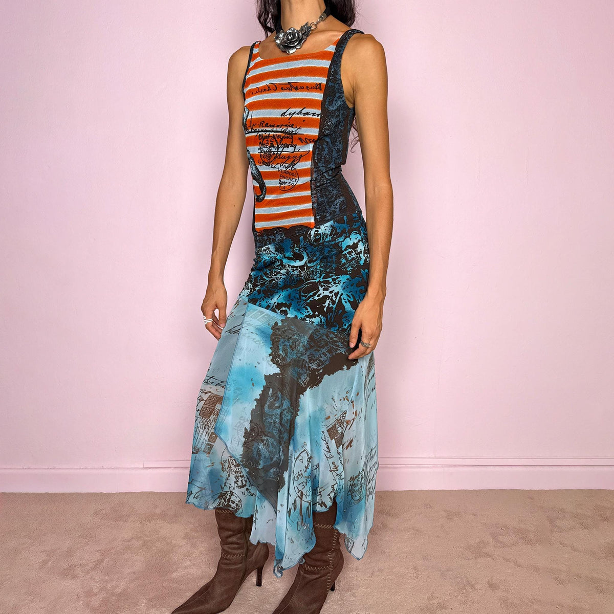 Vintage 2000s maximalist maxi dress featuring a mixed construction that combines fitted printed mesh through the upper body with semi-sheer mesh panels through the lower section, creating a fluid, layered effect. The graphic composition mixes striped, abstract, and handwritten-style motifs in burnt orange, brown, and vivid blue tones, finished with a dramatic asymmetric handkerchief hem for extra movement. A bold Y2K art-to-wear piece with an avant-garde, editorial feel.