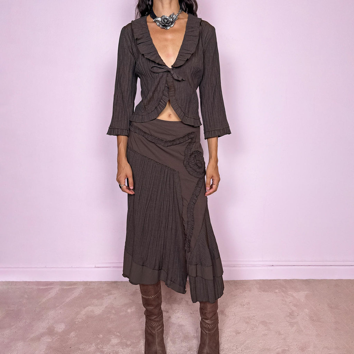 Vintage 2000s brown two-piece set featuring a fitted tie-front top with softly flared 3/4 sleeves and delicate ruffle trim, paired with a matching asymmetric midi skirt. The skirt combines fluid paneling, pleated inserts, ruffled appliqué detailing, and an irregular hem for a romantic deconstructed Y2K silhouette, with a side zip closure. Can be worn high-waisted for size S or slightly lower on the waist for size XS. Made from a non-stretch polyester and viscose blend.